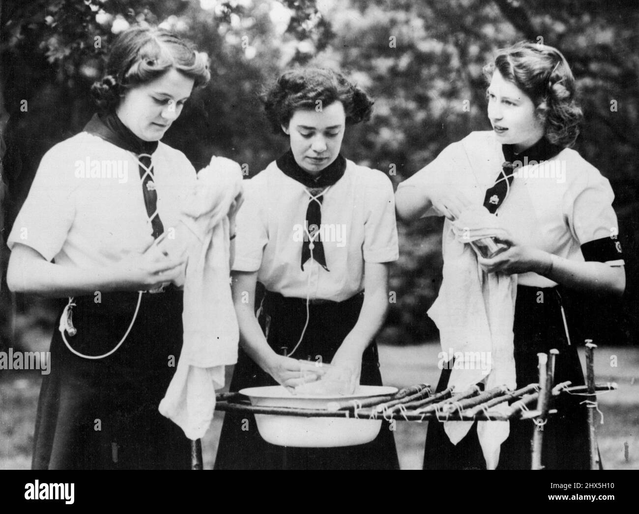 Princess With Girl Guides -- Sea Ranger Princess Elizabeth does her share of the washing-up after an outdoor meal which she helped to cook. Princess Elizabeth and Princess Margaret Rose visited a girl Guides camp. July 25, 1944. Stock Photo