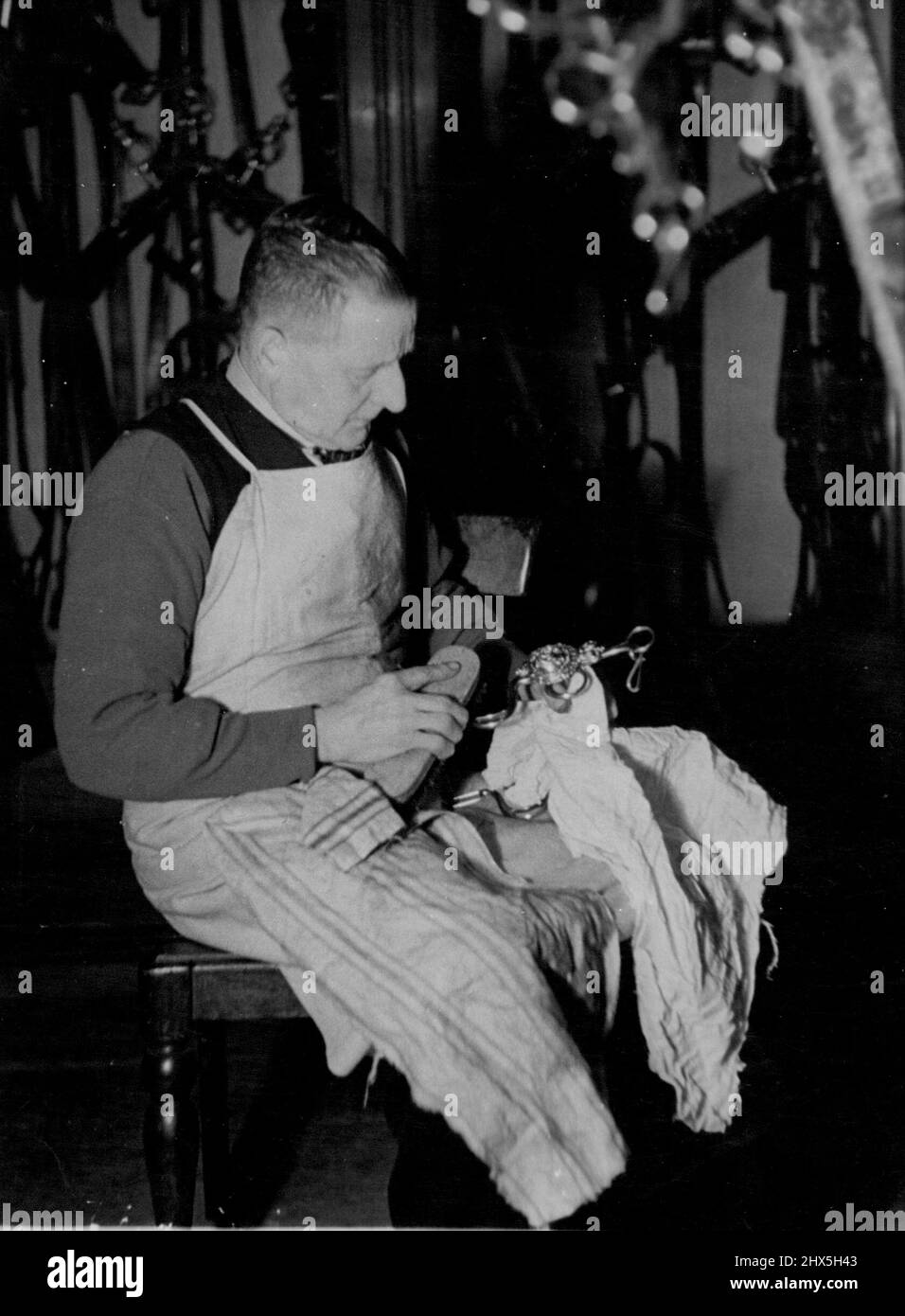 On His Majesty's Service. Coachman J.H. Clarke, 39 years in the Royal Household, knows all there is to know about cleaning the Royal harness. With Mr Croft he is responsible for the cleanliness of the museum pieces, and the furniture in the State Harness Room. May 22, 1946. Stock Photo