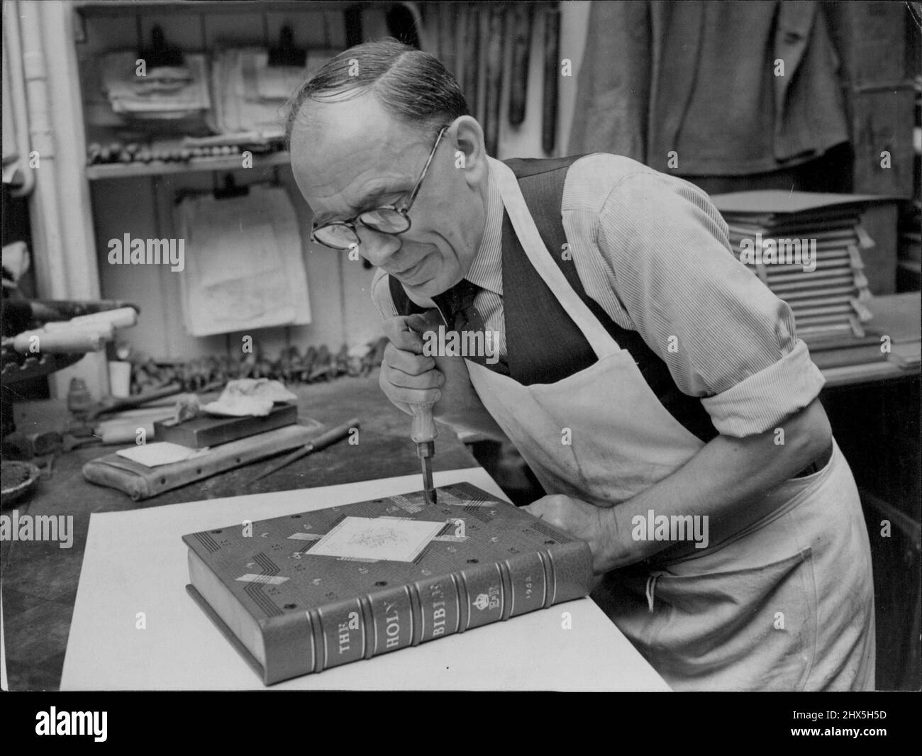 London Craftsman Works on Coronation Bible. Mr. Edgar Turner handtooling with gold leaf the Coronation Bible, which will play an important part in the Westminster Abbey Service. The massive Lectern Bible, one of an edition of twenty-five copies printed by the Oxford University Press is being bound at Messrs. Sangorski and Sutcliffe's book binding works in London. Mrs. Turner, who lives at Forest Hill, London, has been with the firm for 35 years. May 12, 1953. Stock Photo