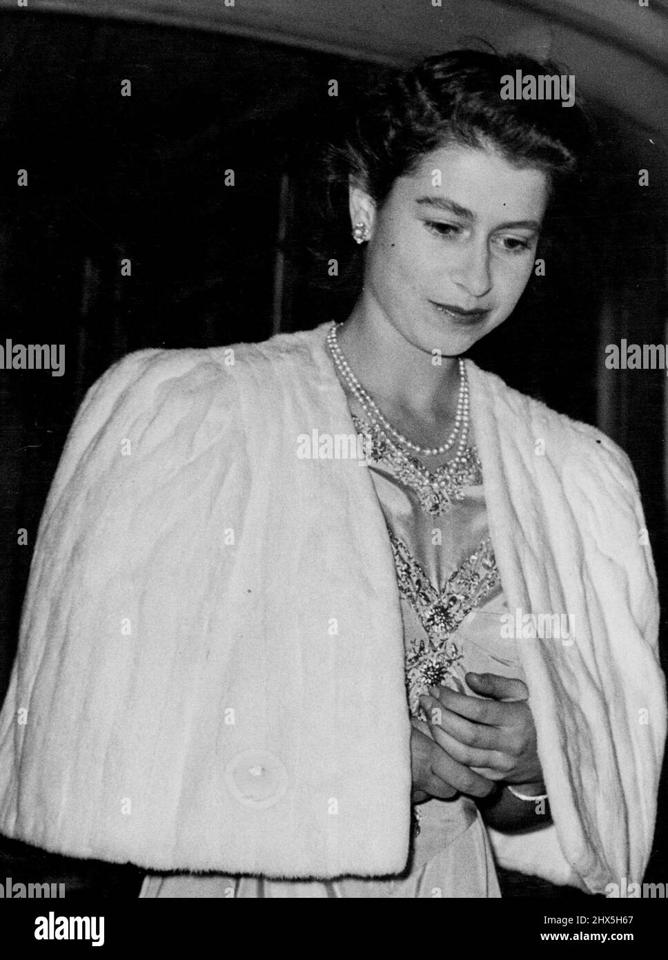 Princess Elizabeth And Lieutenant Philip Mountbatten To Wed; The Princess Attends Private Dinner Party at Dorchester Hotel. Princess Elizabeth - with folded hands - leaving the Dorchester Hotel after the dinner party. After the announcement of the engagement of Princess Elizabeth to Lieutenant Philip Mountbatten (formerly Prince Prince Philip of Greece) the Princess went to the Dorchester Hotel, in London, for a private dinner party - and later the party went to Apsley House, for dancing. July 9, 1947. Stock Photo