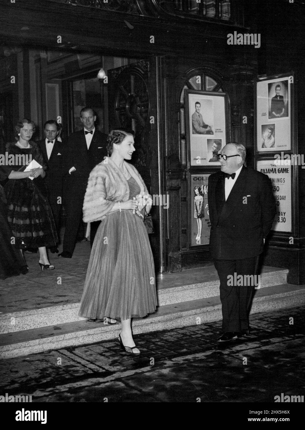 Queen Elizabeth At 'Pajama Game.' Britain's Queen Elizabeth went Tuesday night to see the London version of the smash-hit American musical 'The Pajama Game.' Picture shows the Queen smiling with pleasure as she leaves the theatre at show's end. In background can be seen her consort, the Duke of Edinburgh. November 8, 1955. Stock Photo