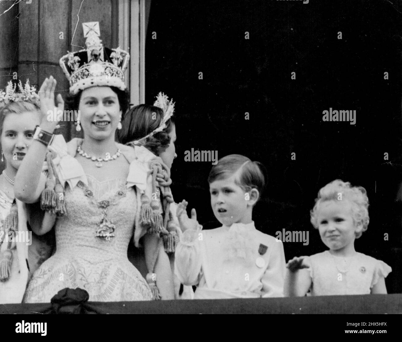 Crowned Queen And Her Children Wave From Palace Balcony -- Smiling and wearing the Imperial State Crown, the Queen is joined by her children, Prince Charles and Princess Anne, in waving from Buckingham Palace balcony to the cheering crowds in front of the Palace after the Coronation to-day (Tuesday). On left, behind the Queen, is Lady Anne Coke, one of the Queen's six maids of Honour at the Coronation. As the Queen, the Duke of Edinburgh and other members of the Royal Family appeared on the balcony, 168 jet fighters flew over in the Royal Air Force salute to the newly-crowned Sovereign. June Stock Photo