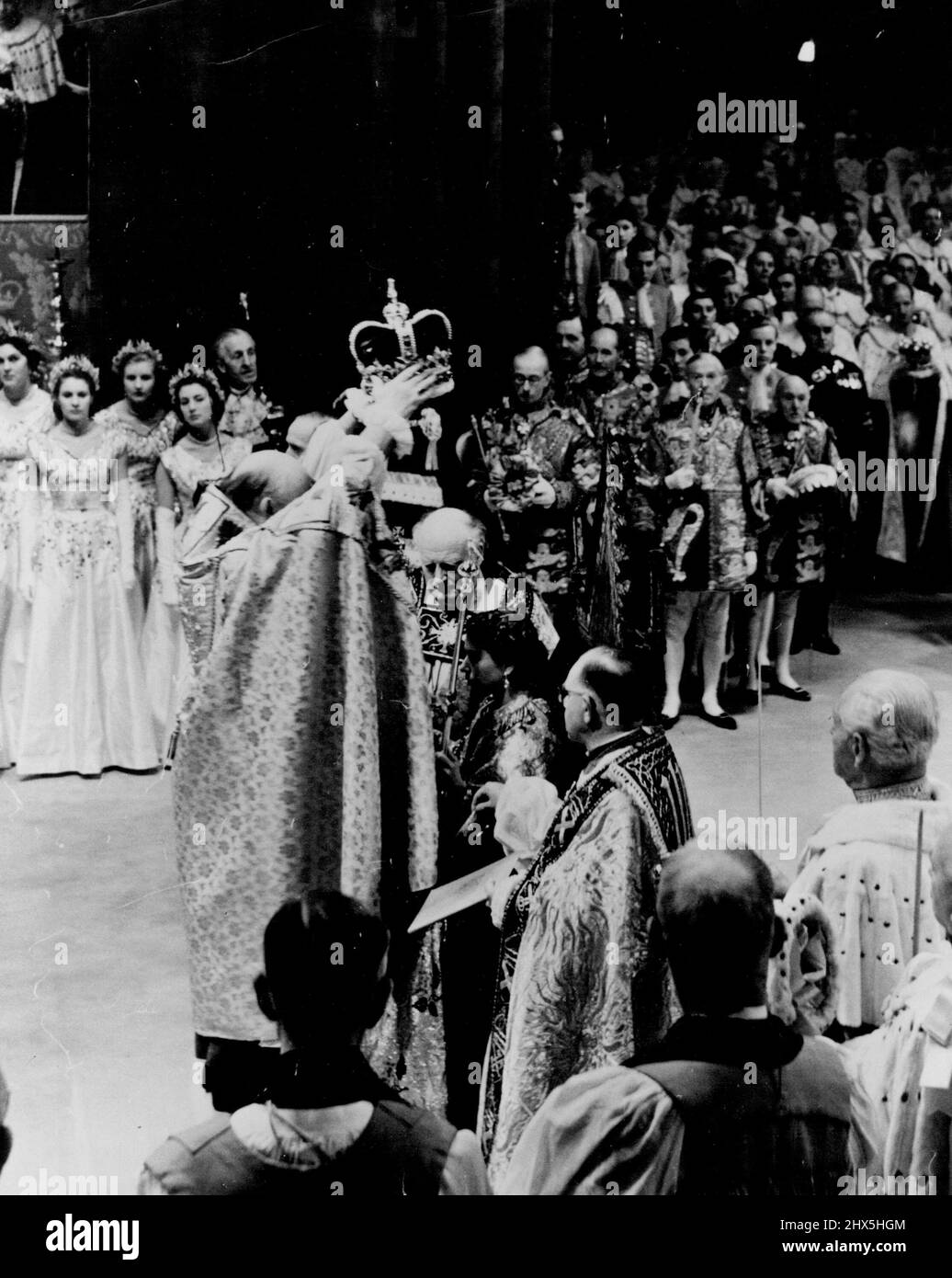 The supreme moment of the Crowning of Queen Elizabeth II. The Archbishop of Canterbury receiving the Crown of St. Edward from the Dean of Westminster, placed it reverently upon the Queen's head. As she was crowned the congregation shouted, 'God Save the Queen;' peers and peeresses put on their coronets, Kings of Arms their crowns, and a fanfare of trumpets was sounded. Outside bells pealed and guns fired a salute. June 02, 1953. (Photo by Daily Mirror). Stock Photo