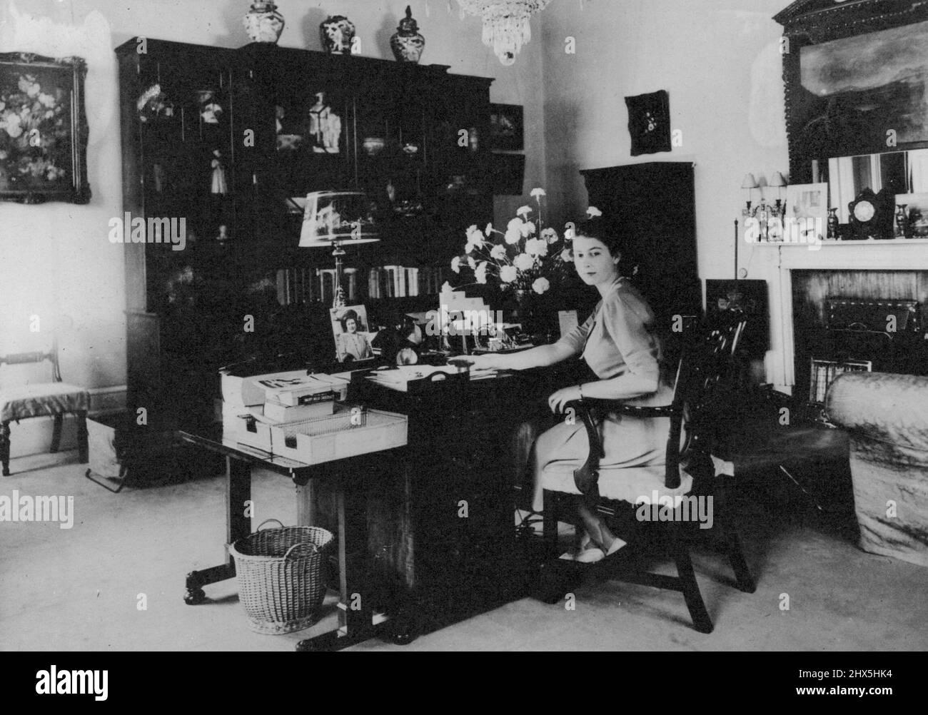 Britain's Princesses At Home In Buckingham Palace -- Princess Elizabeth, who is heir to the throne, settles down to some serious work at her desk. Seen among the businesslike desk equipment is a portrait of the Queen. These intimate pictures show Princess Elizabeth and her younger sister, Princess Margaret, in the privacy of their own room at Buckingham Palace, London. Daughters of King George and Queen Elizabeth, Princess Elizabeth is now 21 and Princess Margaret is 16. Their room, with windows looking out on the Queen Victoria Memorial, provides an interesting glimpse into the girls' Stock Photo