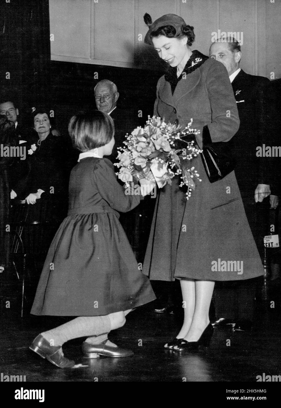 The Queen Visits Girls' School -- Rosemary Kidson, 8, of Leeds, Yorkshire, presents a bouquet to Queen Elizabeth II as Her Majesty arrived at this Royal Masonic School for girls at Rickmansworth, Hertfordshire today March 11. The Queen paid a two-hour visit to the school. There was loud applause when the headmistress, Miss A. Fryer, told the 400 girls that the Queen had asked her if she would allow them an extra day's holiday. March 22, 1955. (Photo by Associated Press Photo). Stock Photo