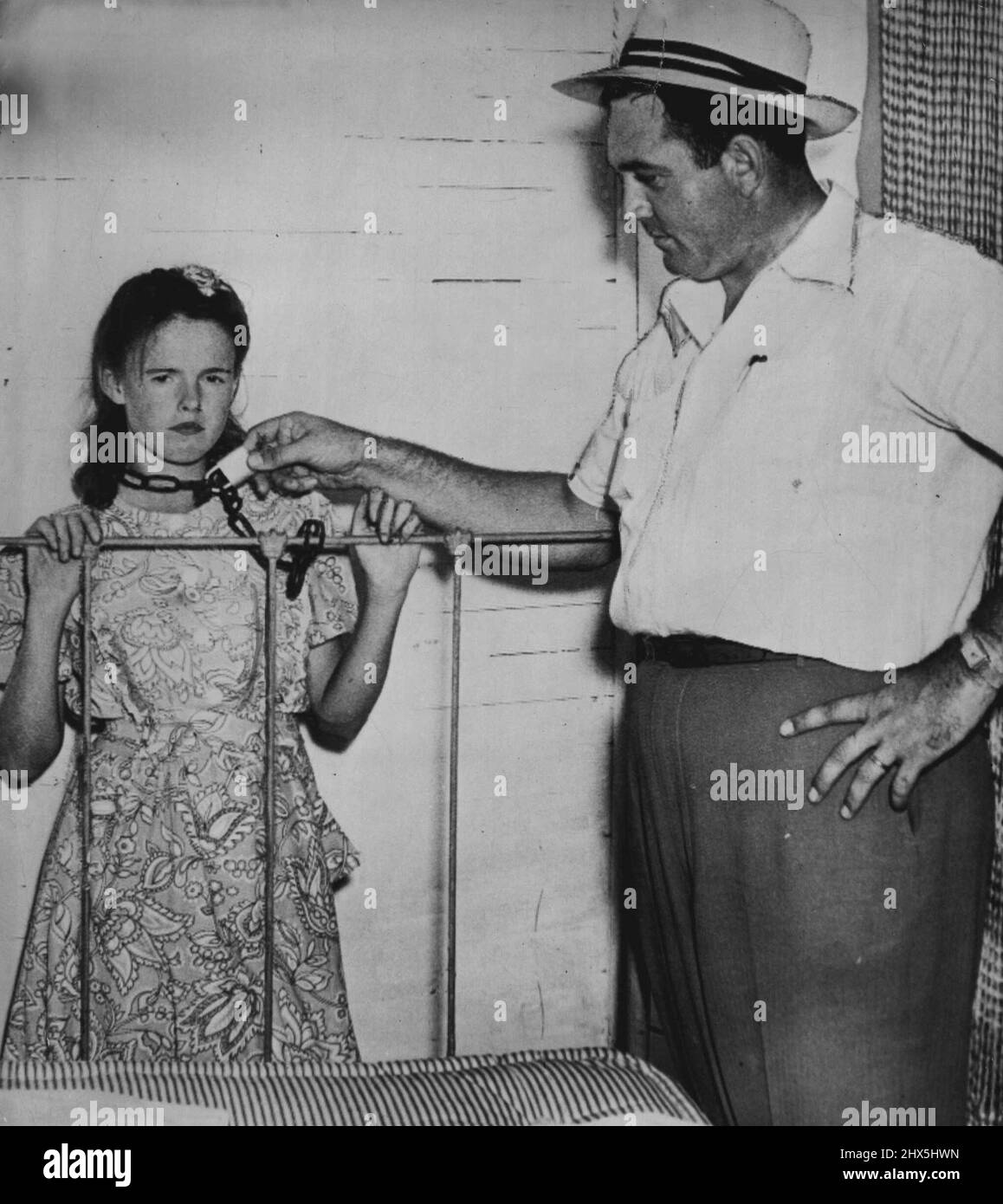 Farm Wife Says She Was Chained -- Blanch Hamby (left) 21-year-old farm wife, shows State Investigator San Allen the position in which she says she was often chained to the foot of her bed during the two years sine her marriage to Lester Bamby, 38. The husband is in Tallapoosa county jail charged, with assault with intent to murder and assault and battery. September 17, 1948. (Photo by AP Wirephoto). Stock Photo