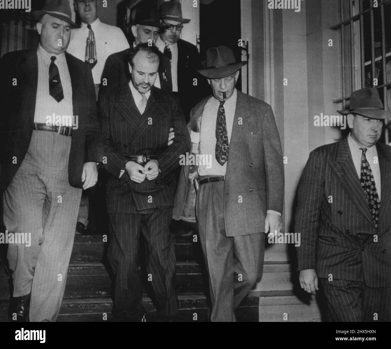 To Prison -- Earl Bircham (handcuffed) leaves courtroom today after sentencing to electric chair for slaying patrol man John Tennyson. Bircham is surrounded by detectives and sheriff's deputies who took him to state prison at Eddyville. October 22, 1949. (Photo by AP Wirephoto). Stock Photo