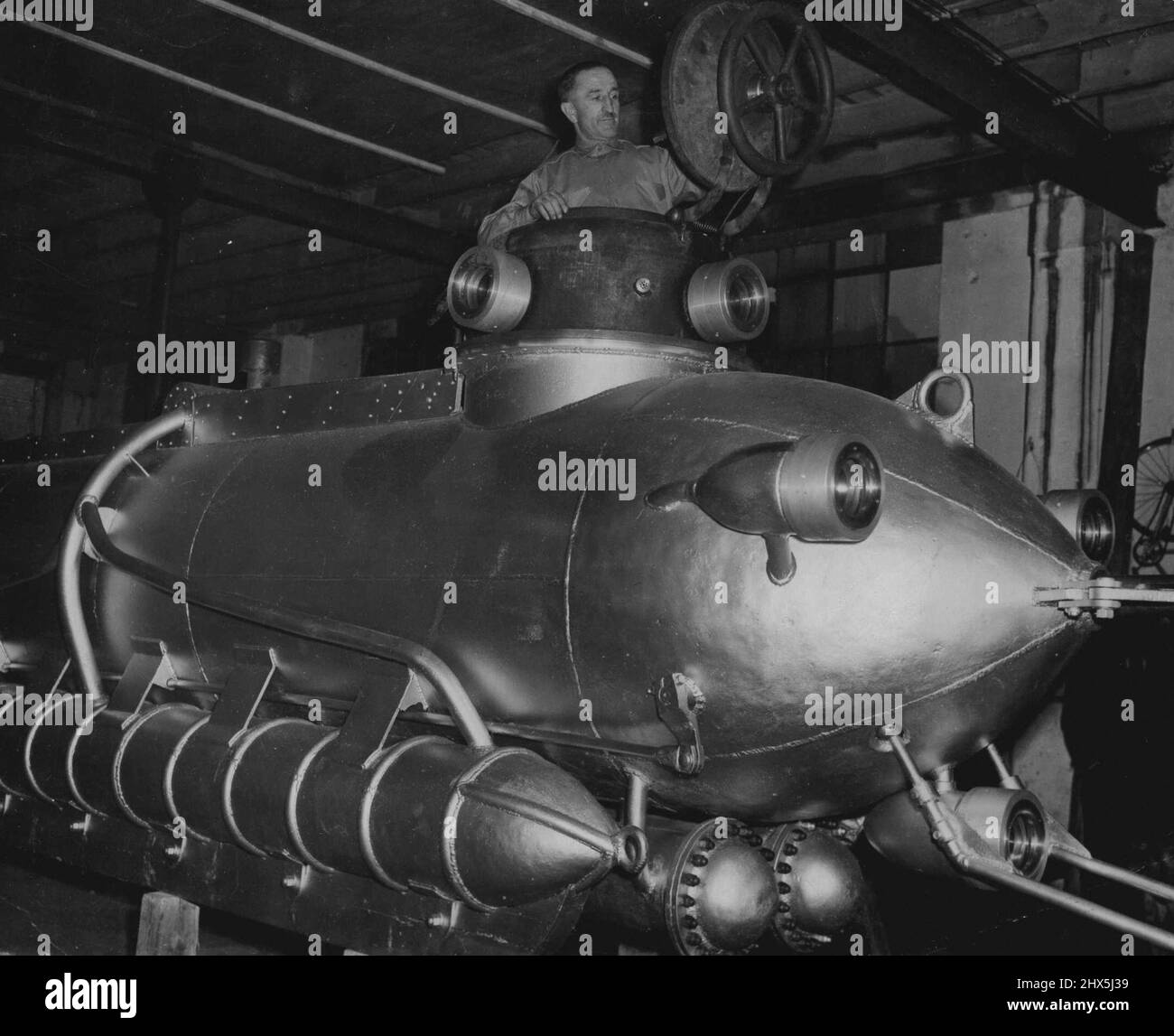 New Midget Italian Scientific Submarine -- Pietro Vassena in the conning tower of his midget submarine, known as the 'C.3', picture made at the inventor's workshop at Lake Como, Italy. Pietro Vassena, 50-year-old Italian inventor will shortly carry out tests at Lake Como with the midget two-man treasure-seeking and grapping submarine which he has designed. The craft, 25 feet. Long and four feet six inches wide, can descend to a depth of 2,400 feet and remain submerged for 20 hours. on the surface it is powered by a 40/50 H.P. Car engine and when submerged,by an electric 20 h.p. motor which Stock Photo