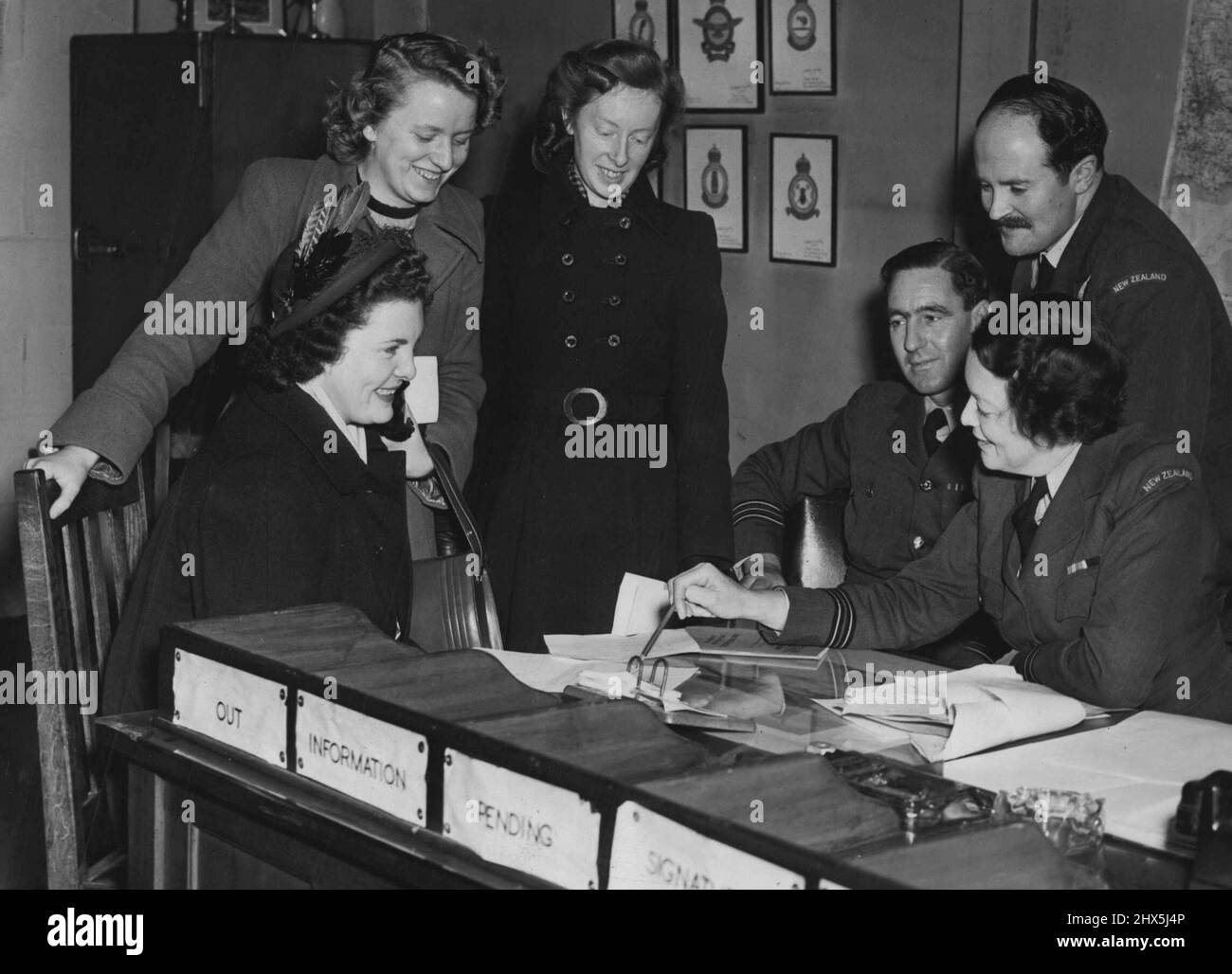 Ex- WAAFS Rush to Join N.Z. Air force Higher Pay Attracts 400 -- Patricia Sweeney of Liverpool (six years in the WAAF) sitting, and Anne Anderson of Fraserburgh, Aberdeen, Scotland (2 yrs in the WAAF) and Helen Stirling of Glasgow (WAAF for 4½ yrs (standing behind) are interviewed today by woman Flight Officer E.J. Peat; Squadron leader M.B. Furlong R.N. Z.A.F. and Flt Lieut N.J. Ingram R.N.Z.A.F. In response to an appeal for recruits in this country (by the Royal New Zealand Air Force) for former A. T. S., W. A. A. F. s and W. R. N. S. some 400 British girls habe aplied to join the New Stock Photo