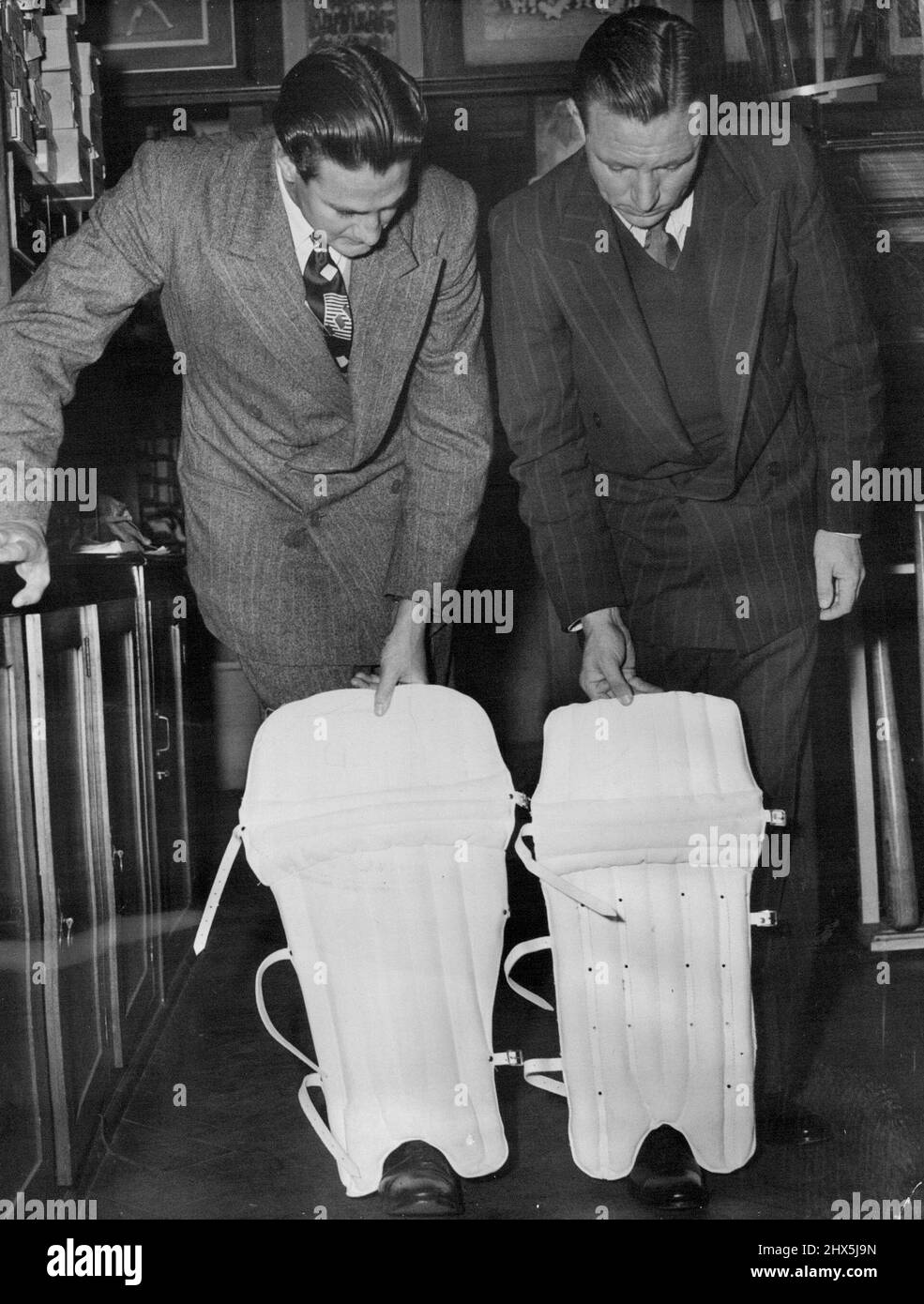 Pads: The new (held by Keith Miller, (left) and the old (held by Ray Lindwall). Note protecting flap on the newer pad. September 26, 1949. Stock Photo