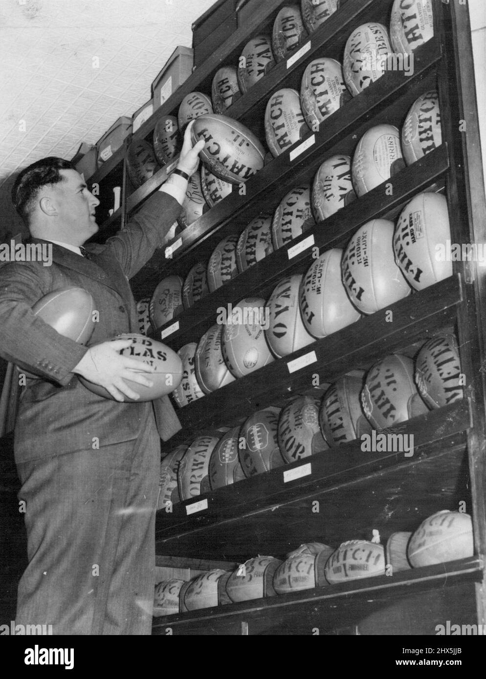 Footballs in shining rows, as yet Unmuddied after the hefty kicks of Victorian footballers, line the walls of Melbourne sports shop. Melbourne's football season will start tomorrow. April 21, 1939. Stock Photo