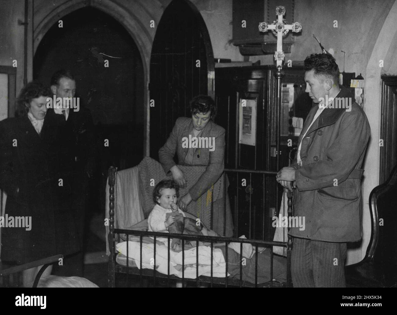 Family Squat in church. After a fruitless search for somewhere to live, Mr. and Mrs. F. Offord and their baby daughter settled in the vestry of a church in Bexley Heath, England. They previously lived in a children's nursery, but were given notice to quit. December 14, 1946. (Photo by Associated Newspapers). Stock Photo