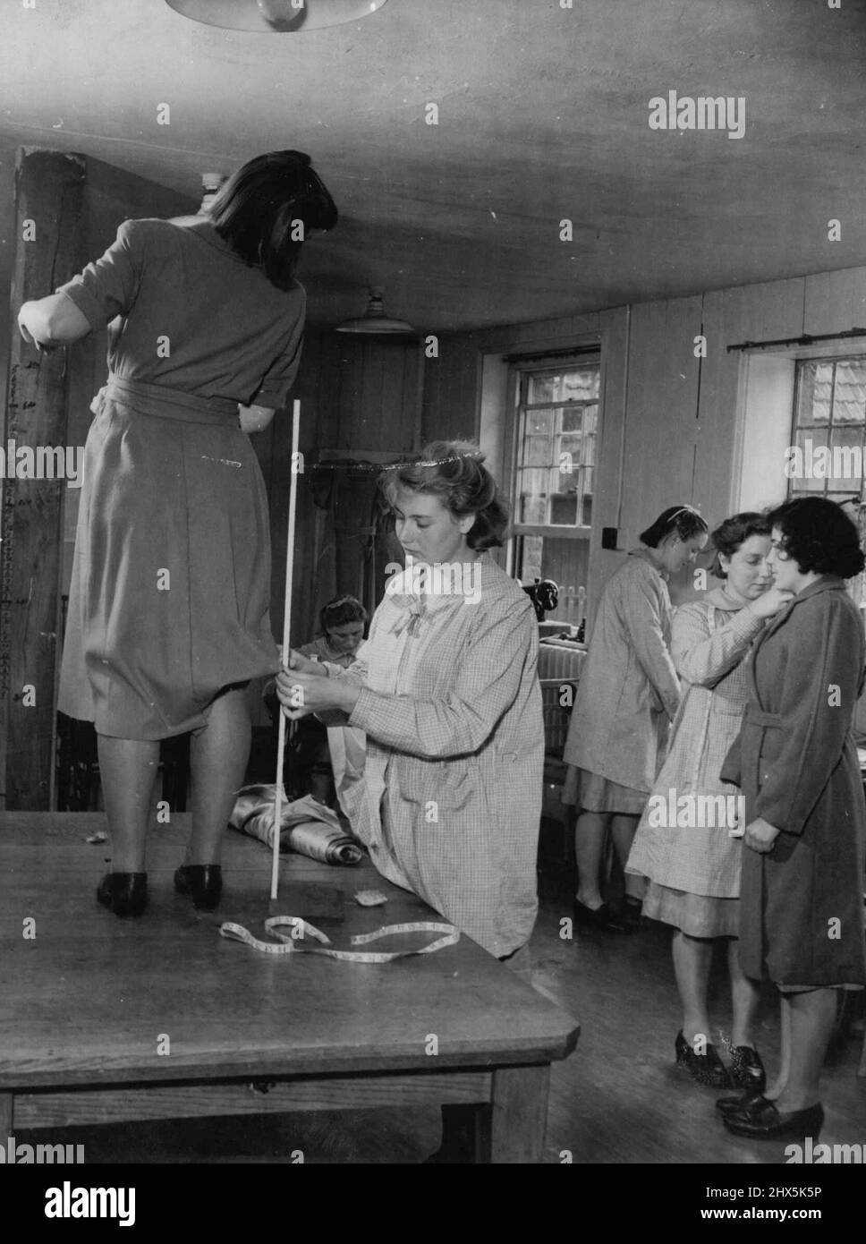 Denham Court Girl's School -- Dressmaking Class. Home Office Schools or Approved Schools are intended for the education and training of boys and girls between the ages of 10 and 17 sent to them by the Courts either was young offenders or as needing care and protection. The schools are approved and inspected by the Home Office and costs are borne in equal proportions by the Exchequer and the local authorities out of local rates. In 1945 there were about 150 Approved Schools. These photographs were taken at Denham Court, a Senior Girls' School run by the Middlesex Education Authority. The girls Stock Photo