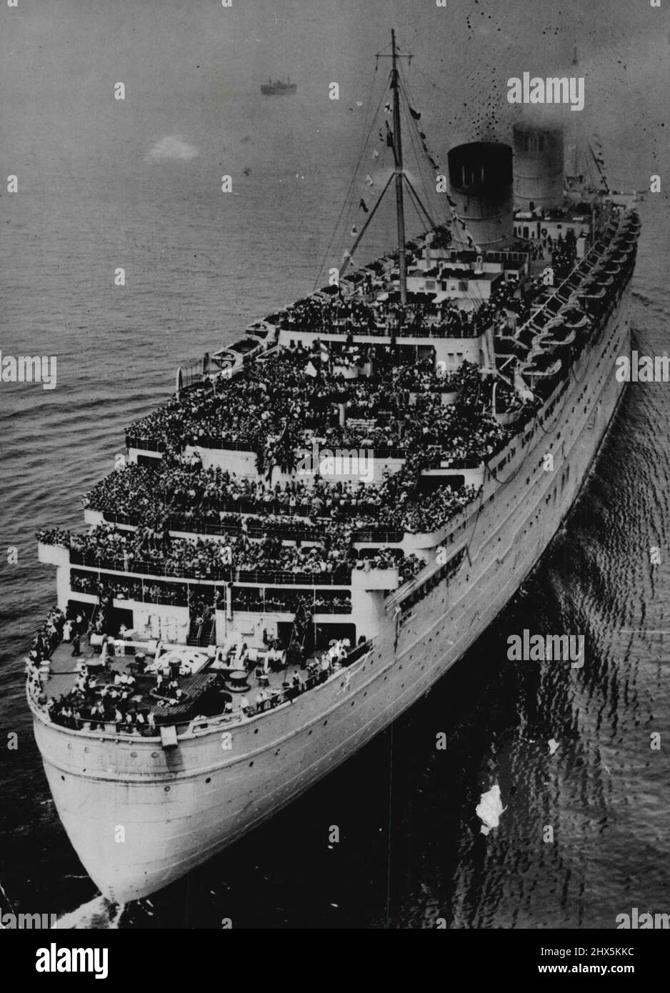 U.S. Soldiers Return Home On The Queen Elizabeth - With her decks crowded with 13,113 American fighting men, the Queen Elizabeth, the world's largest ocean liner, steams up New York Bay on June 29, 1945. Among the homecoming troops aboard are 13,658 men of the U.S. Eighth Army Air Force and general hospital units, as well as 1,200 Navy men and 442 Army nurses. All are returning from the European theater of war, and many will soon see service in the Pacific. The 85,000-ton troop ship made her first voyage across the submarine-infested Atlantic in Larch, 1940. This is her first official visit Stock Photo