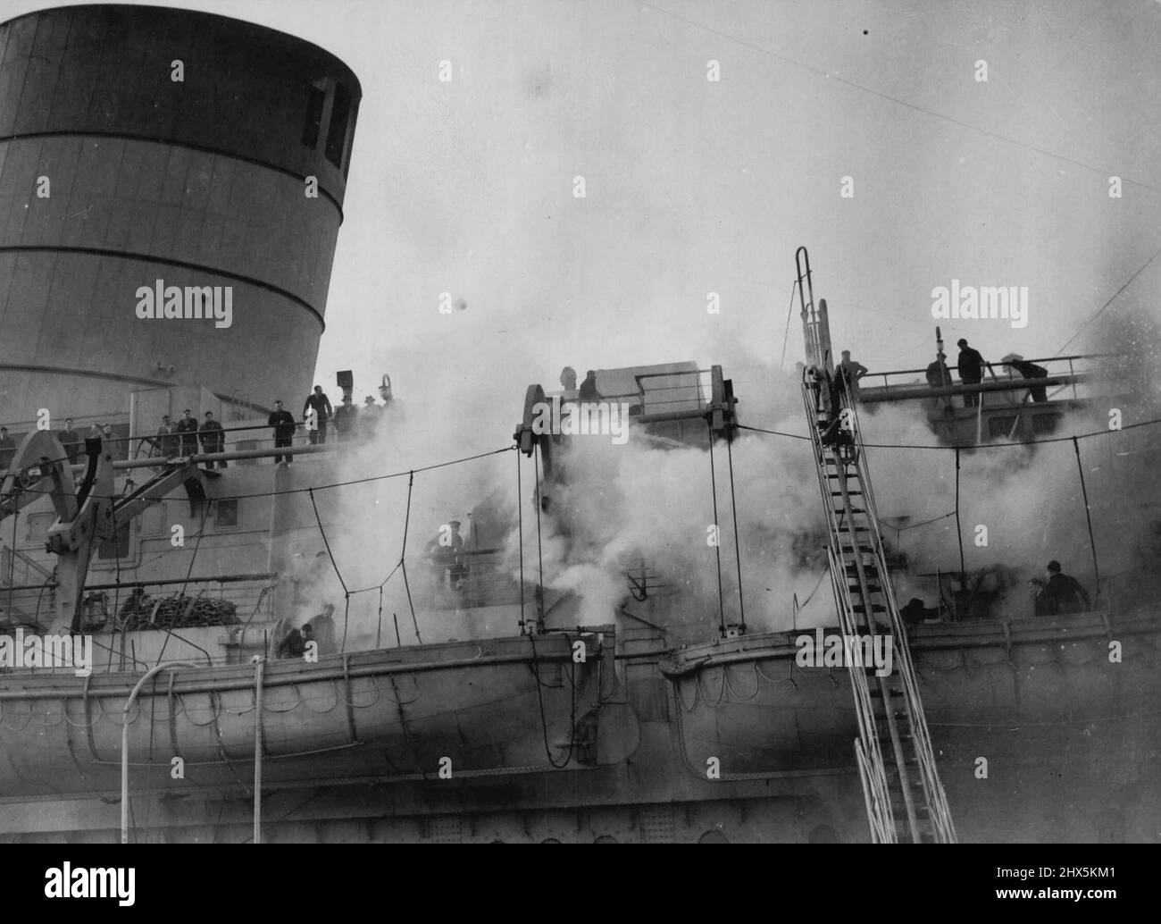 Mystery Fire In Queen Elizabeth -- Firemen and dock hands are seen fighting the blaze on board the Queen Elizabeth, today March 8, which broke out in the bedding store of the isolation hospital on the Port side of the promenade deck. A Mystery fire broke out in the world's largest liner - The Queen Elizabeth, in dock at Southampton, today March 8. Police assisted by Cunard White Star officials are probing the mystery of the outbreak, which luckily confined to the isolation hospital. It has been officially stated that the damage to the £6,000,000 liner is slight. March 08, 1946. (Photo by Stock Photo
