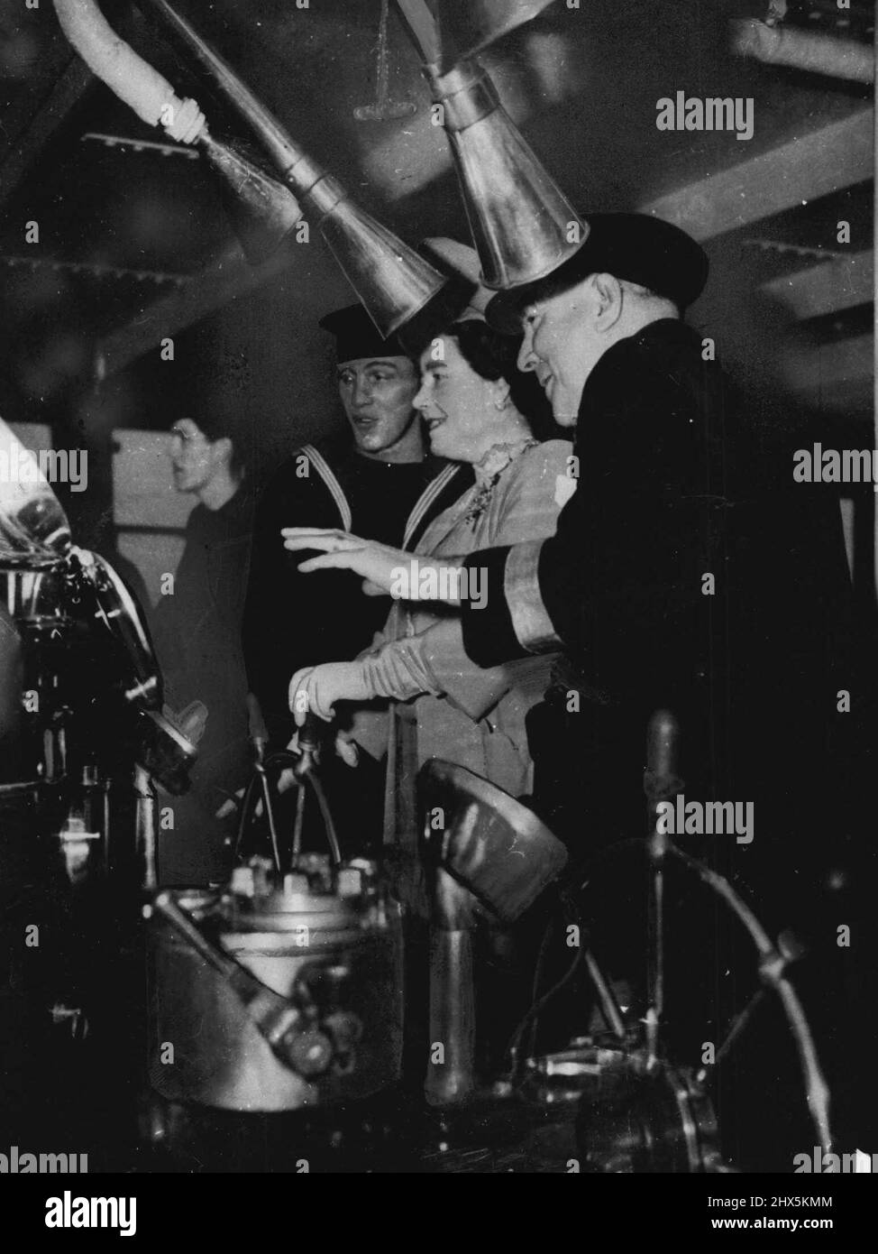 Queen Elizabeth Steers Her Name Ship -- This historic picture shows Her Majesty Queen Elizabeth steering her name ship, the gigantic liner 'Queen Elizabeth,' during the vessel's speed trials in the Firth of Forth, October, 1946. The Queen, advised by Commodore Sir James Bisset (nearest camera) relieving the Quartermaster at the wheel while the liner speed over the 'measured mile' at thirty knots. January 01, 1946. (Photo by Associated Press Photo). Stock Photo
