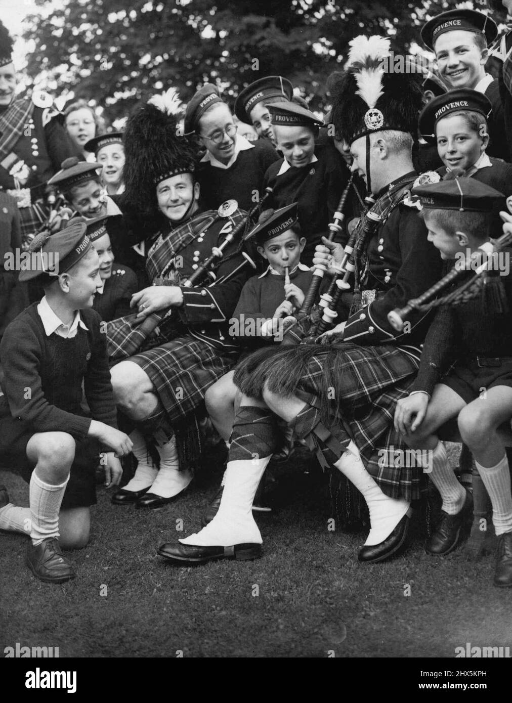 Edinburgh Festival -- A case of fraternisation between the pipers and the provencal choirboys. Little boy blowing the bagpipes. Is II year old Heiri Piery from Marseilles. His comment afterwards : 'C' est formidable'. August 24, 1950. (Photo by D. Johnson, Paul Popper Ltd.). Stock Photo