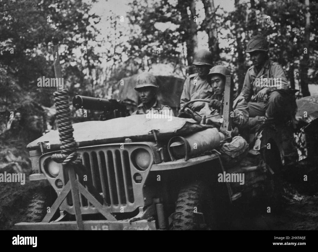 American Of Japanese Descent Jeep Along A Muddy French Road -- Riding a jeep armed with a heavy machine gun, American soldiers of Japanese ancestry watch for snipers as they move down a muddy French road. A trailer loaded with equipment is towed behind them. Several thousand of these young men, whose ancestors came to the U.S. from Japan, are demonstrating their loyalty by fighting beside their fellow Americans against the enemy in Italy as well as in France. November 20, 1944. (Photo by U.S. Office of War Information Picture). Stock Photo