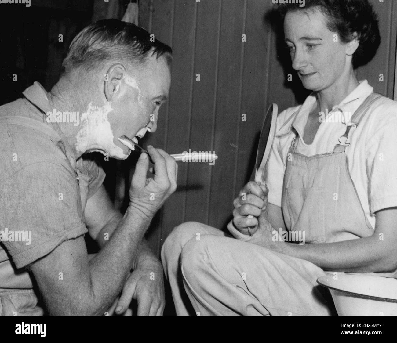 Left: A Shaving problem was solved for Adrian Anderson, of Old Toongabble, when Nida Rixon, of Gerringong, held a mirror for him outside the horse boxes at the Royal Show. March 15, 1951. Stock Photo