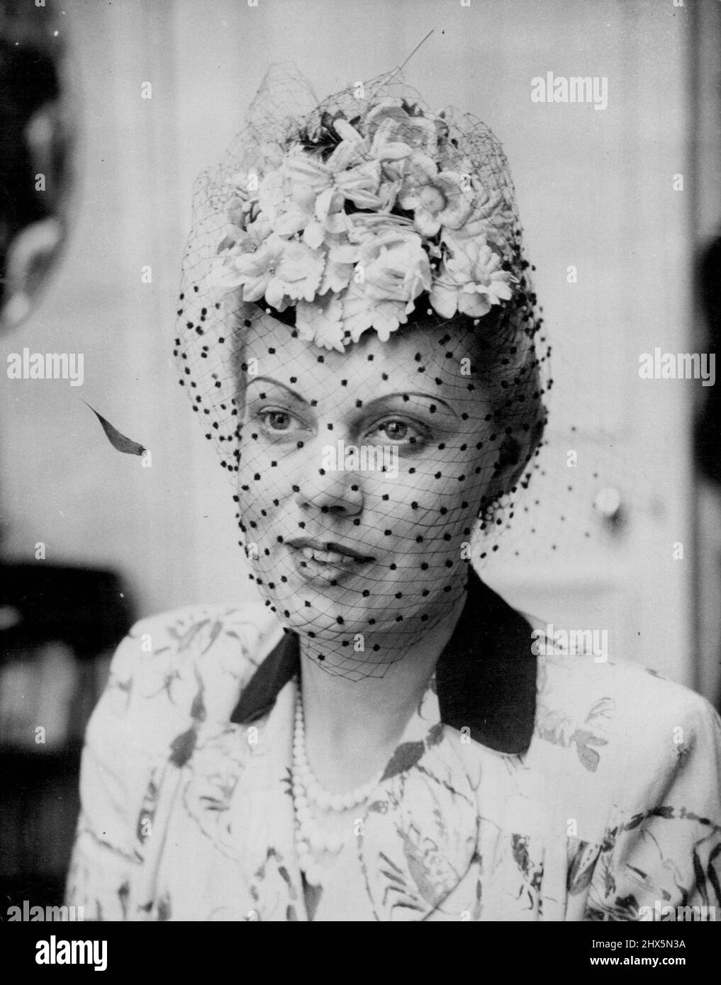 Note of Originality -- Lovely opera singer Constance Shacklock, who is pictured here remodels her own hats in between her singing performances. The wife of Mr. Eric Mitchell, repetiteur on the musical staff of the Convent Garden Opera Company, she is seen here wearing a delightful flowered toque (roses, violets and spring blossom) with a black veil, one of the hats she remodeled herself. September 11, 1949. Stock Photo