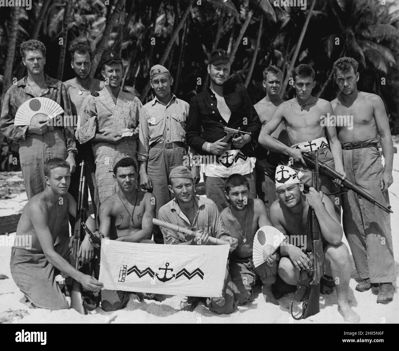 Marines With Pacific Battle Trophies -- After having cleared Tarawa of the enemy, these Marines wear and display some of the Japanese trophies they picked up in battle. This group went to Apamama after Tarawa. Left to right (standing); PFC Robert M. Phillips, Milwaukee, Wis.; Cpl. Raymond W. Boese, Bloomer, Wis.; PFC Herman Kaufman Chicago, Ill.; Lieut. J. B. McPeters, Killen, Ala.; Sgt. Stanley V. Grooms, Everett, Mass.; PFC Peter A. Olson, Berkeley, Calif.; Pvt. Alvin G. Shulz, Lake Mills, Wis.; and Cpl. Charles F. Wolfe, Ada, Ohio. Seated: PFC Donald R. Nielson, Neenah, Wis.; Pvt. Oscar J. Stock Photo