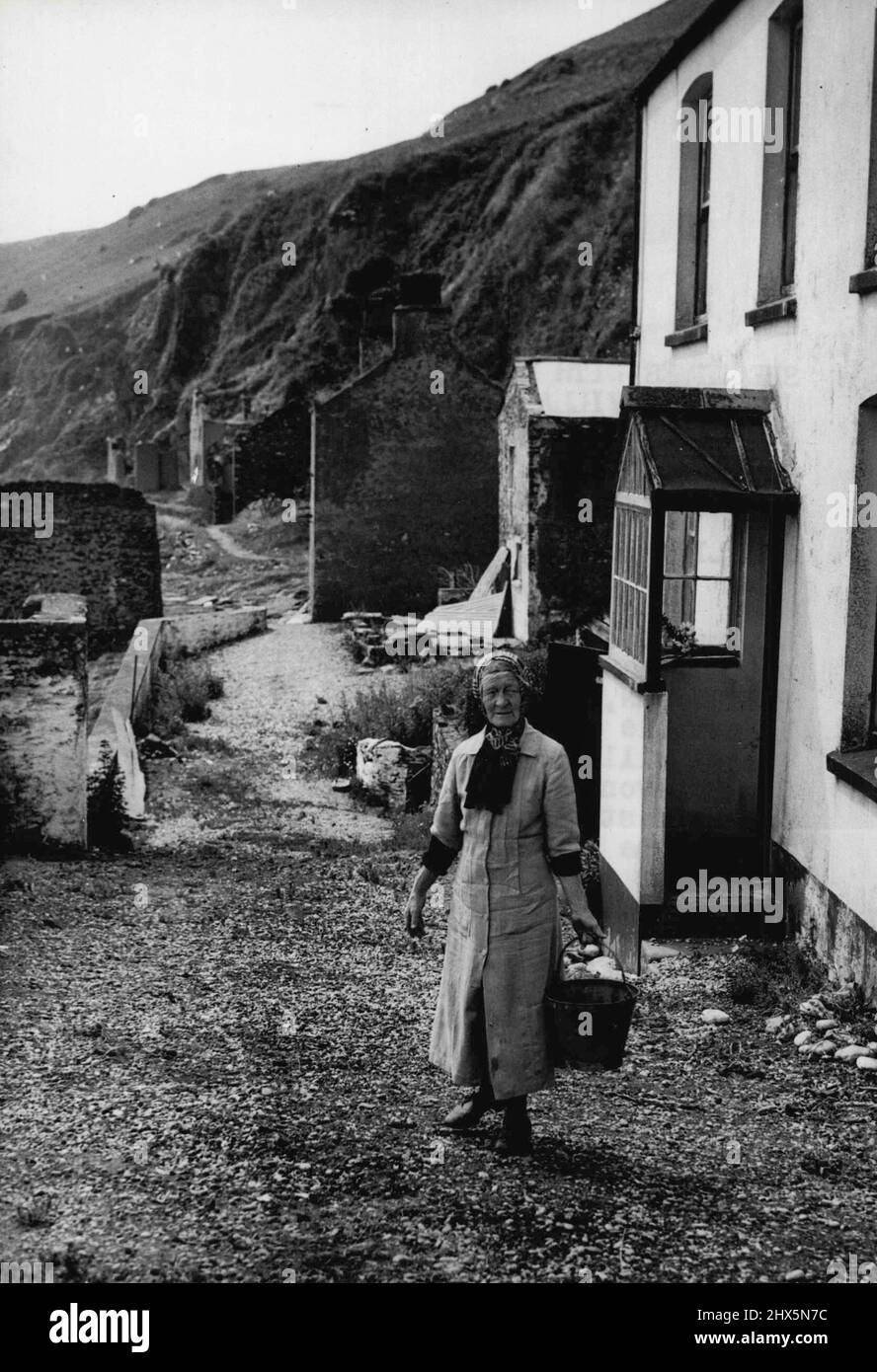 She Lives With Memories - In 'Ghost Village -- A tempest; of 38 years ago took everything out Her memories from Elizabeth Pretty John, a stout-hearted 70 - who is now the only inhabitant of the 'ghost village' of South Hallsands in South Devon. Here she stands outside her home. Before the storm struck in 1917, South Hallsands was a prosperous little fishing village. Afterwards, only Elizabeth and her brother were left, Now, the brother is dead and Elizabeth lives with her remembrances grave and gay. She has had an Invitation to live in London, but has refused because, she says, 'There is no Stock Photo