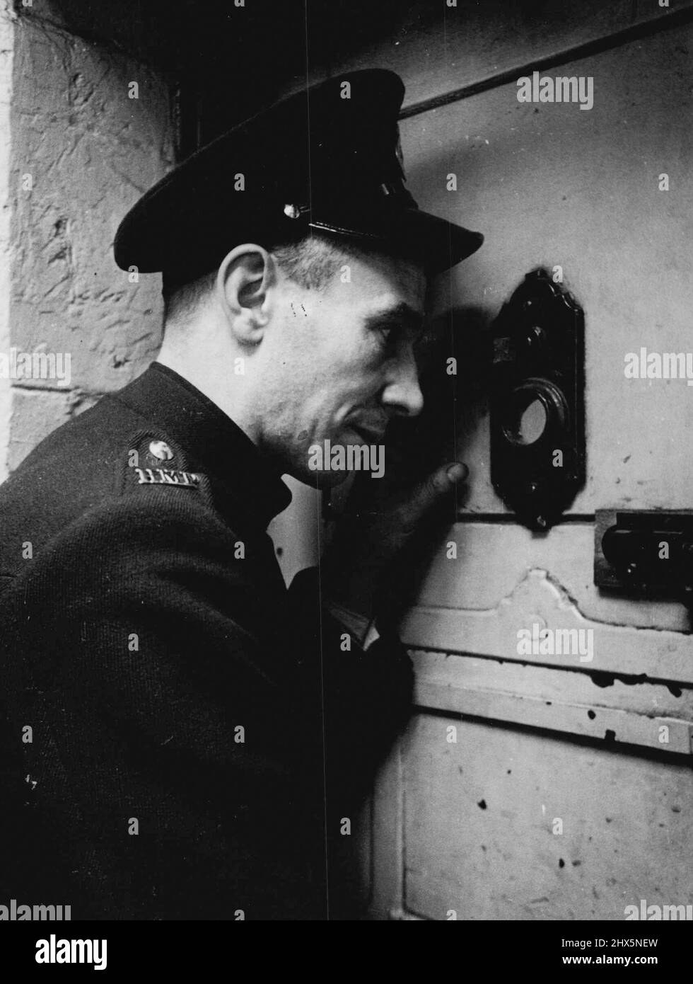 Prison Officer Davidson operates a peephole to keep tab on the prisoners in their cells. April 12, 1950. (Photo by Bert Hardy, Picture Post). Stock Photo