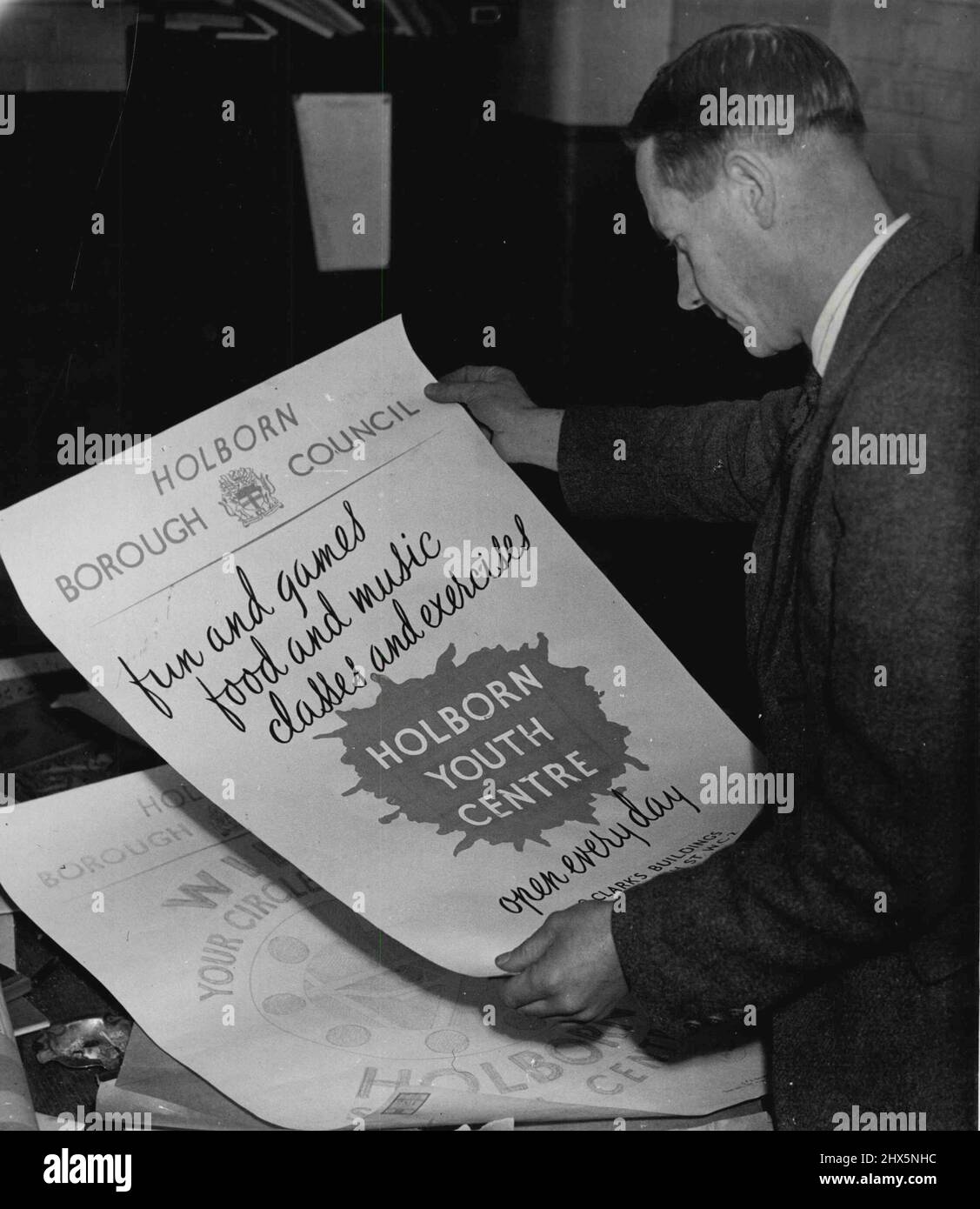 Holborn Youth Centre -- Organiser and leader at the Holborn Youth Centre is Mr. A. Collins. Aged 38, Collins has just retired from the Army Education Corps after five war years in India, Egypt and France. A schoolteacher by profession, he has the knack of handling youngsters without fuss and without asserting his authority. No is responsible not only for the Youth Centre but also for Holborn's Social Centre for Adults which is housed in the same building; the Borough Council are his employers. - Mr. Collins is seen in his office with a new poster he designed to publicise the Youth Centre Stock Photo