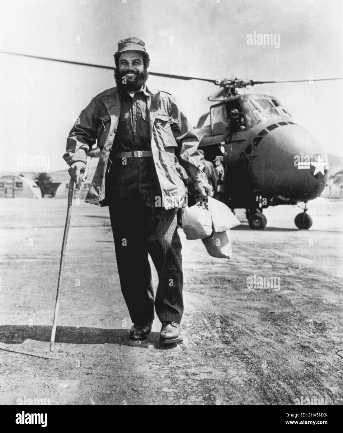 A Happy Greek -- Heavily bearded Chletzos Konstantinos, of Limnos, Greece, shed of his Communist prisoner uniform and wearing a complete new issue of UN clothes walks with a cane as he clutches a small bundle of belongings, as he leaves a helicopter at the 121st evacuation hospital near Korea, Konstantinos was among the group in the first day of the historic transfer of prisoners at Panmunjom. April 22, 1953. (Photo by AP Wirephoto). Stock Photo