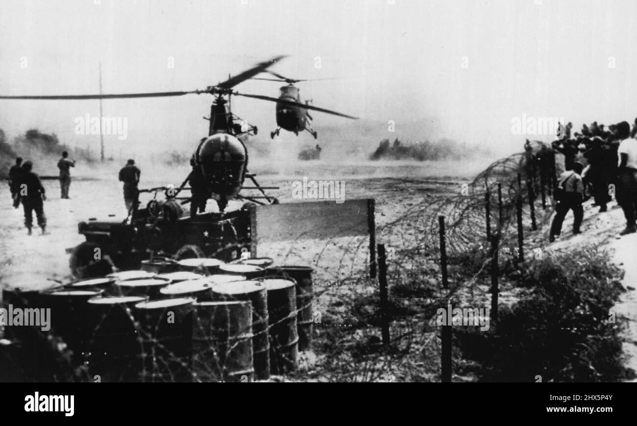 Emmisaire's Helicopters Return -- The big H-19 helicopter which carried UN cease-fire emissaries to Kaesong hovers, right center, while a smaller H-5 lands behind barbed wire enclosure after their return to the advance peace camp north of Seoul. Newsmen jam against wire as the helicopters return. July 8, 1951. (Photo by AP Wirephoto). Stock Photo