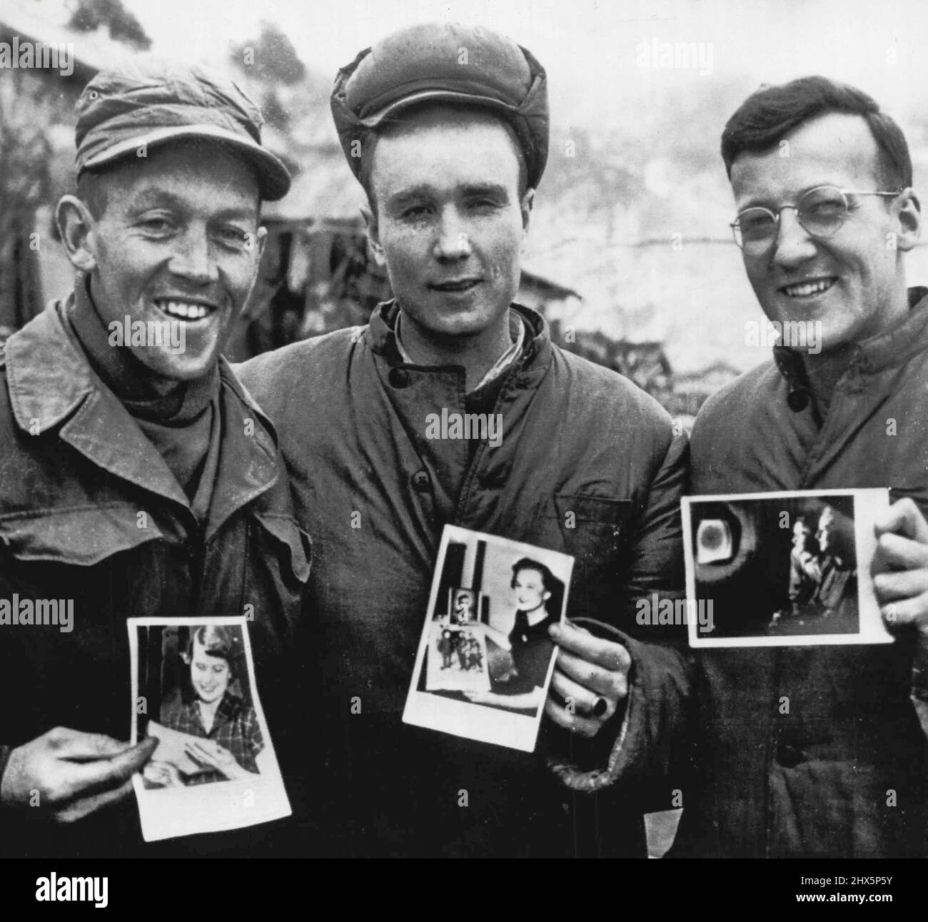 Pictures From Home -- Three Americans, prisoners of war of the Communist in North Korea proudly display pictures of their wiles. The pictures once moved on the Associated Press Wirephoto network, were mailed to Japan and thence to Panmunjom and from there to the prison camp. The pictures of the wives were made when their husbands pictures were published as part of a number of exclusive photos made by Frank Noel, Associated Press Photographer who is also a prisoner of the Reds. Frank did a retake when these pictures showed up at the prison camp. Left to right the men are: Lieut.Harold Stock Photo