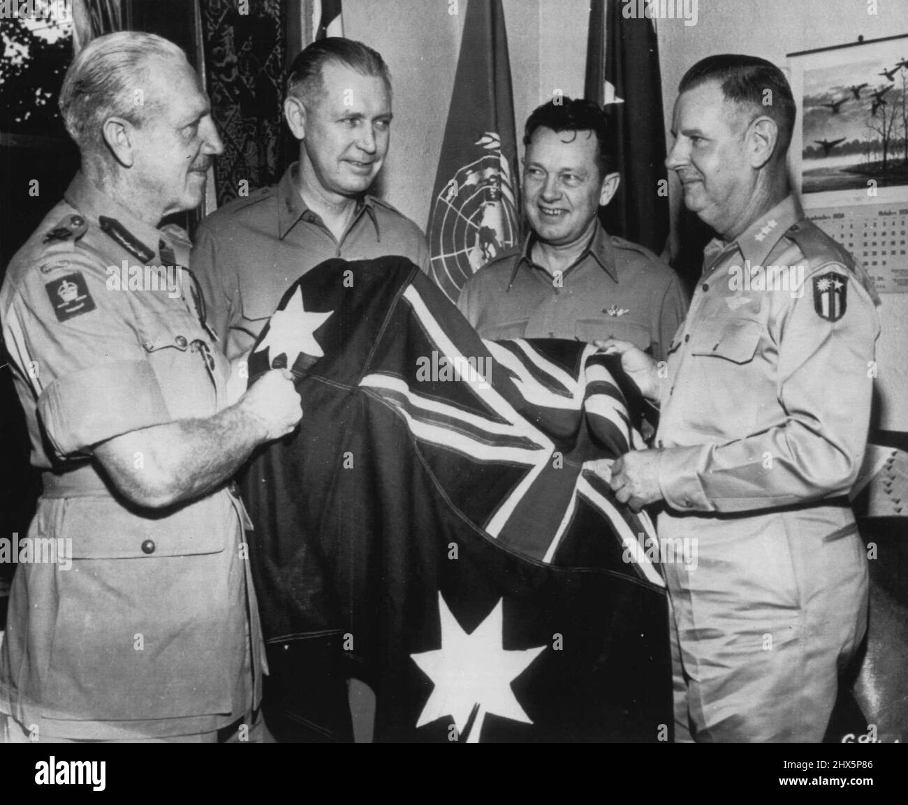 Close coordination between Australian United States Air Force units was the highlight of the above scene (Oct.13) as Lt. Gen. Sir Horace C.H. Robertson (left), commanding the British Commonwealth Occupational Forces, presents the national flag of his country to Lt. Gen. George E. Stratmeyer (right) Commanding General, Far East Air Forces. Mr. Gens. O.P. Weyland(center, left) and L.C. Craigie (center, right), witness the ceremony. October 16, 1950. (Photo by Associated Press). Stock Photo