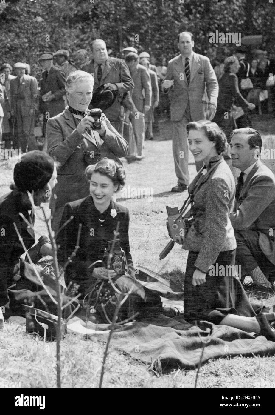 The Queen and Princess Margaret, while attending the International Horse Trials Badminton, joined with others in taking snaps of some of the contestants on the third final day. H.M. The Queen at Badminton - Left to right: Mrs. David Somerset, H.M. the Queen, Princess Margaret and Mr. David Soemrset, enjoying a joke, while watching who Jumping. H.M. the Queen, Princess Margaret and other members of the Royal Family, again attended the International Horse Trials at Badminton, on Friday, the third and final day. April 25, 1953. (Photo by Fox Photos). Stock Photo