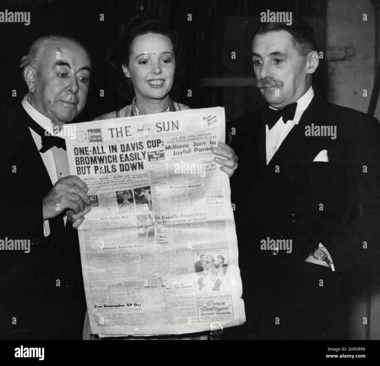 'The Voice Of London' -- George Robey, Jessie Matthews and Jack Train, of the I.T.M.A. gang, three of the popular stars of the special all-star Royal Wedding broadcast at the Theatre Royal, Drury Lane, taking a look at the 'Sydney Sun' backstage. August 29, 1949. Stock Photo