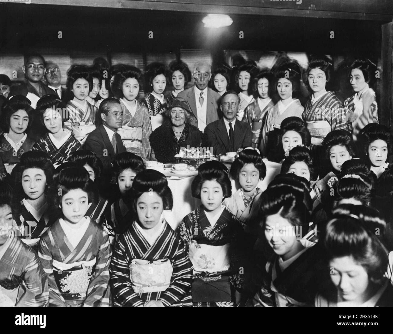 The League Of Nations White Slave Commission Visits Geisha School In Japan -- Dr. Bascom Johnson of the united states, seated at the right, with members of the league of nations white slave commission, during a visit to the geisha quarter of Tokyo. The geisha school at which this picture was made was established last year as a means of training geisha girls in modern methods of entertainment - ballet dancing, singing, English conversation, etc., seated next to Dr. Johnson is Dr. Aima Sunquist, second member of the commission which has been authorized to conduct the inquiry into the traffic in Stock Photo