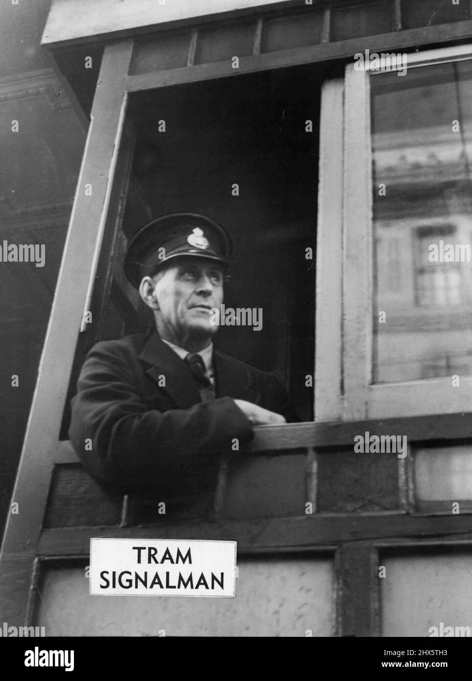 Tram Signalman - ' ...Because I'm king in my own little castle,' says signalman Arthur Markham. He's the man who sits up in the little tram signal - box at the King - street intersection. 'No one interferes with me up here unless it's that traffic cop down there,' he said, peering down from his 10ft. tower. 'Our ideas about traffic don't always coincide.' He watches over his trams like a mother, and sometimes frowns reproachfully at the ordinary cars and taxis turning left and right below. 'Th Stock Photo