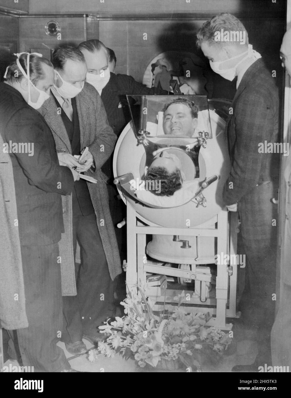 Snite Sails For Shrine Of Miracles -- From his iron lung which was been his home since 1936, 28-year-old Fred Snite, jr., infantile paralysis victim talks to reporters aboard the S.S. Normandie as he sailed from New York May 16 on a pilgrimage to Loudres, France, The Shrine of Miracles. May 16, 1939. (Photo by Associated Press Photo). Stock Photo