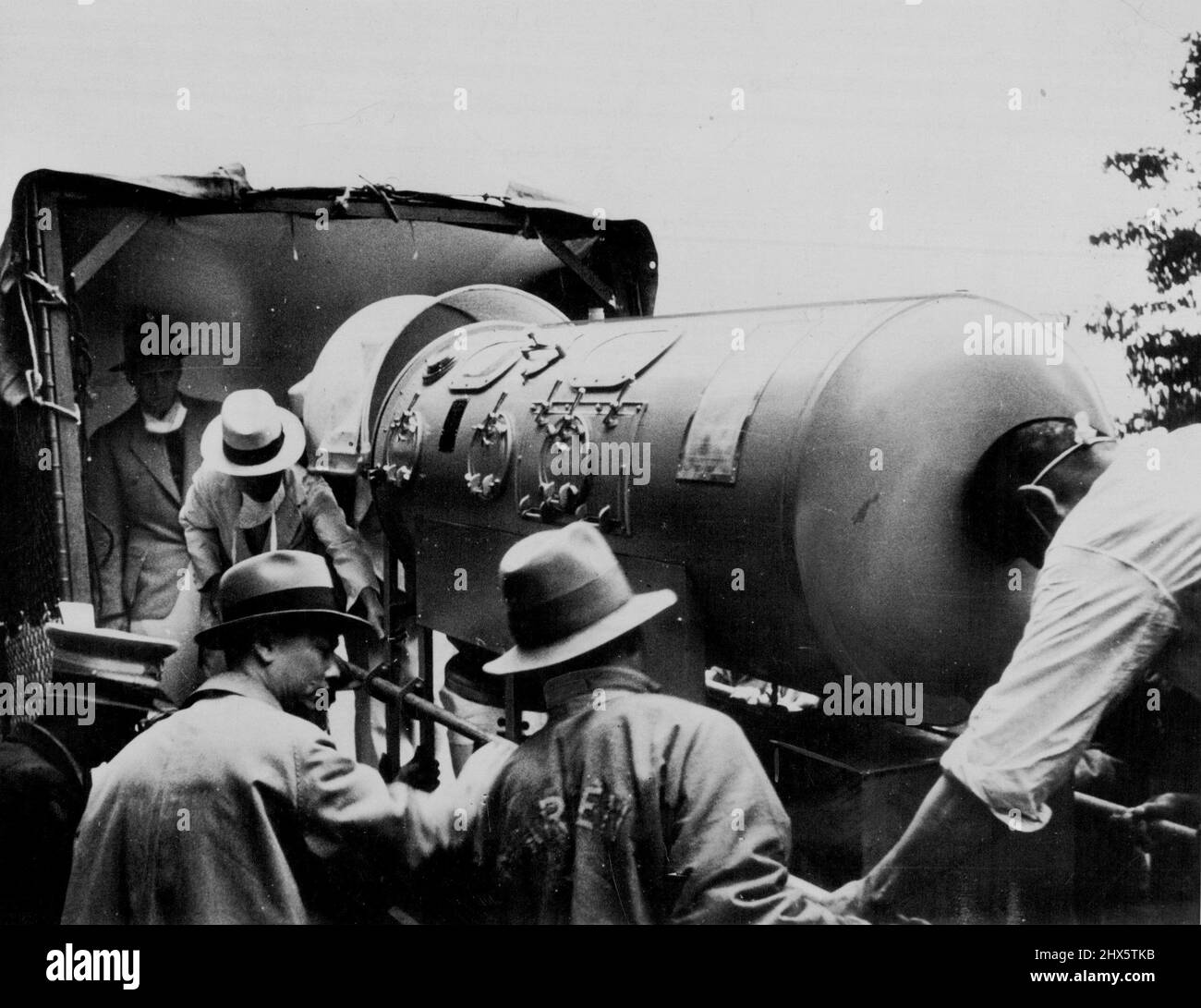 American attendants adjusting the 'Iron lung,' the respirator in which Frederick J. Snite, jun., was taken from Peking, China to America. Snite, the son of a wealthy Chicago merchant, was suffering from infantile paralysis. Before being taken to America. Snite was confined in the 'Iron lung' for 15 months. July 13, 1937. Stock Photo
