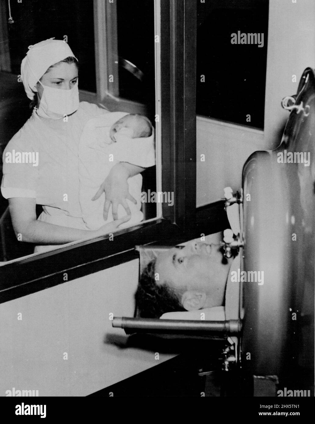 Snite Sees Baby Daughter For First Time - Fred Snite Jr., who has lived in an 'Iron Lung' for the past four years, gets his first view of the 8½ pound daughter born to his wife, as his portable 'Lung' was wheeled to the window of the hospital nursery. September 25, 1940. (Photo by Acme). Stock Photo