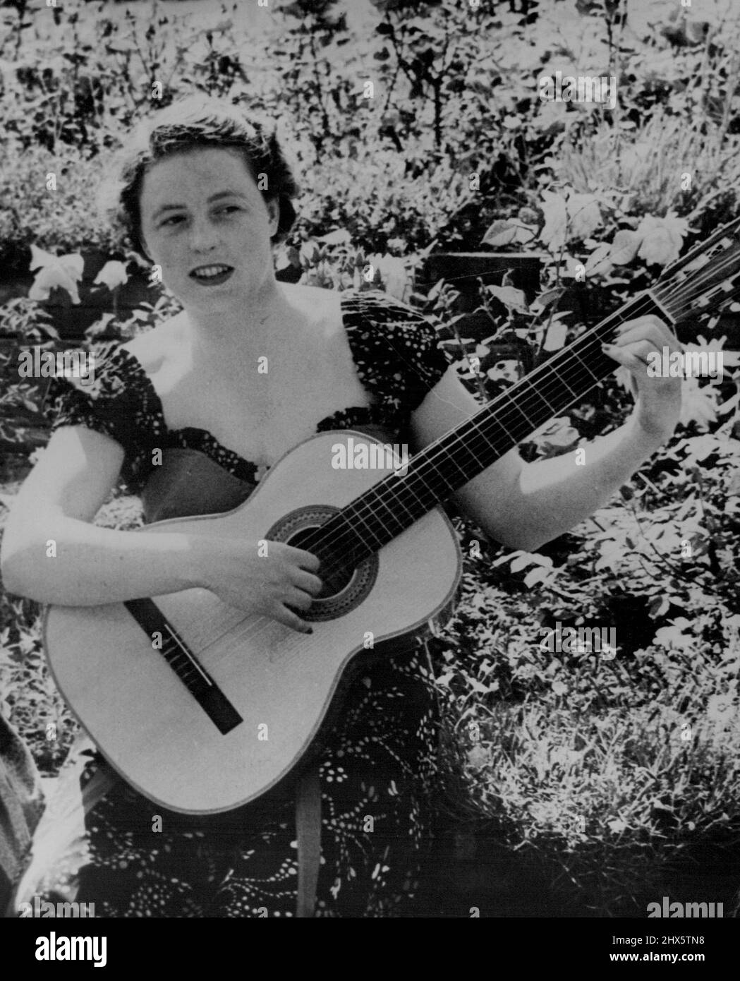 You Do Know Her -- Recognise her? She's a British girl known to audiences all over the world, but not for her guitar playing. Horsewoman Miss Pat Smythe was relaxing in the garden with the six-string Spanish guitar which is one of her favorite out-of-saddle pastimes. August 16, 1955. (Photo by Reuter Photo). Stock Photo