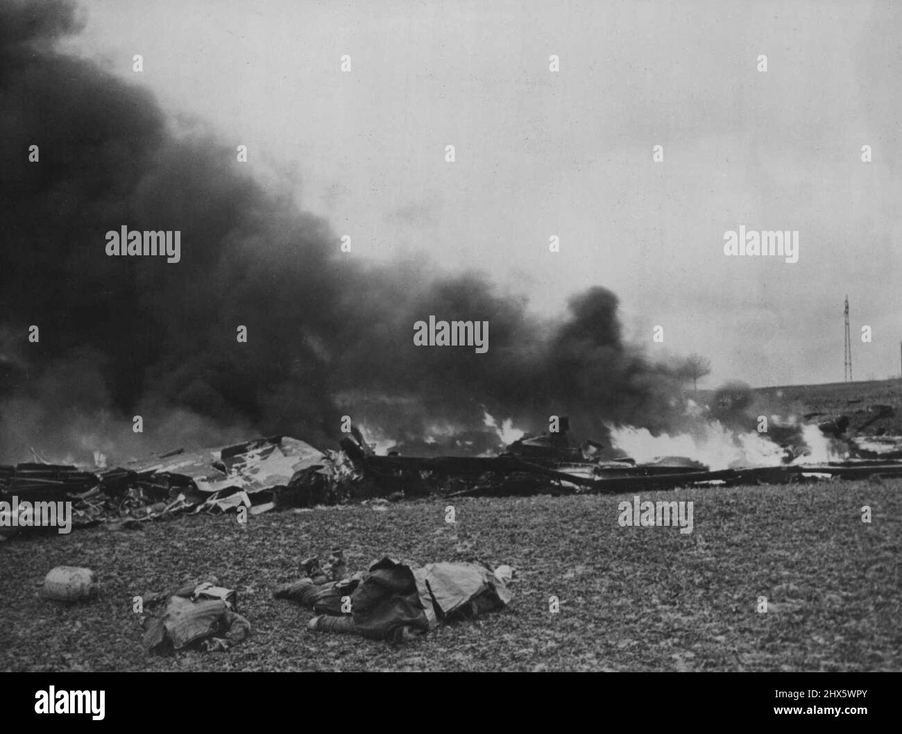 Flaming Death Of U.S. War Plane -- Three dead crew members of a U.S. B-24 Liberator lie next to the blazing wreckage of their bomber somewhere in France. A column of black smoke marks the funeral pyre of, one of the thousands., of American planes supporting the Allied ground offensive against the Germans in Western Europe. January 19, 1945. (Photo by U.S. Office of War Information Picture). Stock Photo