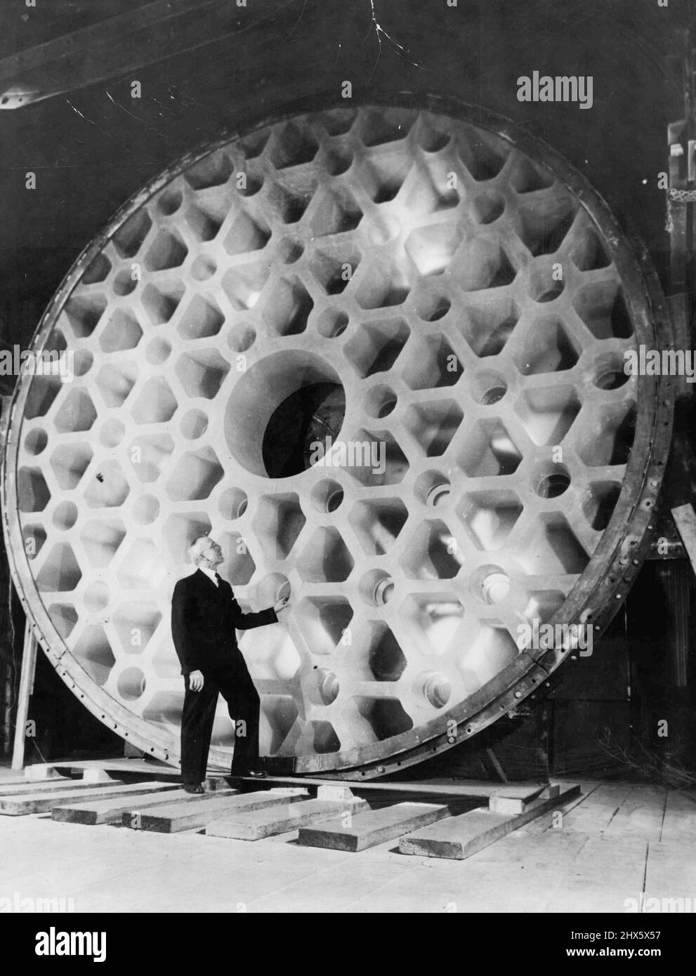 World's Largest Telescope -- John L. Thomas, treasurer of the Corning glass works, contemplates the world's largest piece of glass, the 200-inch telescope disc now being prepared for shipment from corning to California. February 22, 1936. (Photo by Associated Press Photo). Stock Photo