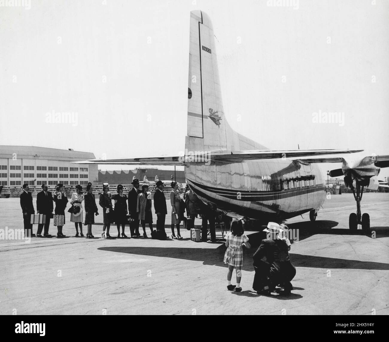 All Aboard For Air Travel Everywhere! Carrying their own baggage, passengers board the newest Lockheed regional transport, the Saturn, conceived by Lockheed to fill the need for a special kind of airplane to meet the exacting performance, payload and economy requirements of small towns served today only by surface carriers. Hundreds of people were questioned by Lock-heed's experts to see just what this regional transport should look like. They wanted to know what the Saturn should carry in the w Stock Photo