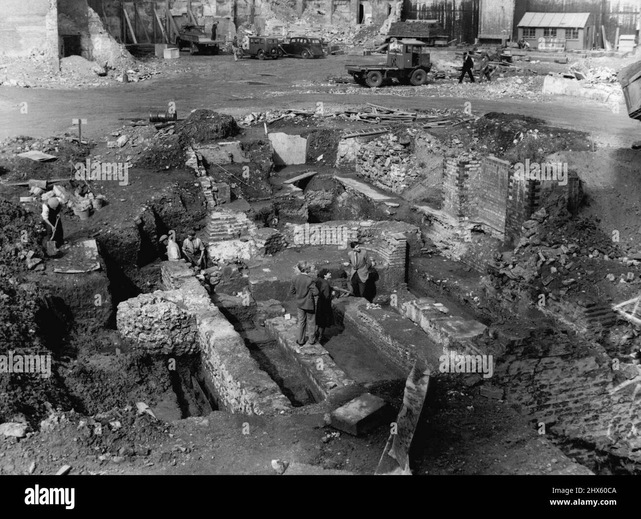 Buried For 1600 Years. Workman Thought It Was A 'Stone' -- A view of the site in Wallbrook. The head of Mithras was found in the hole to the top of the ladder on left. Mr. F.W. Grimes is seen right, with two colleagues at work on the site. Digging on the site of an ancient Roman Temple near the Mansion House yesterday workman Sam Thomas dug up what he thought was just a stone. An Archaeologist thought otherwise and the stone was identified as the marble head of the Pagan God Mithras. The head. D Stock Photo