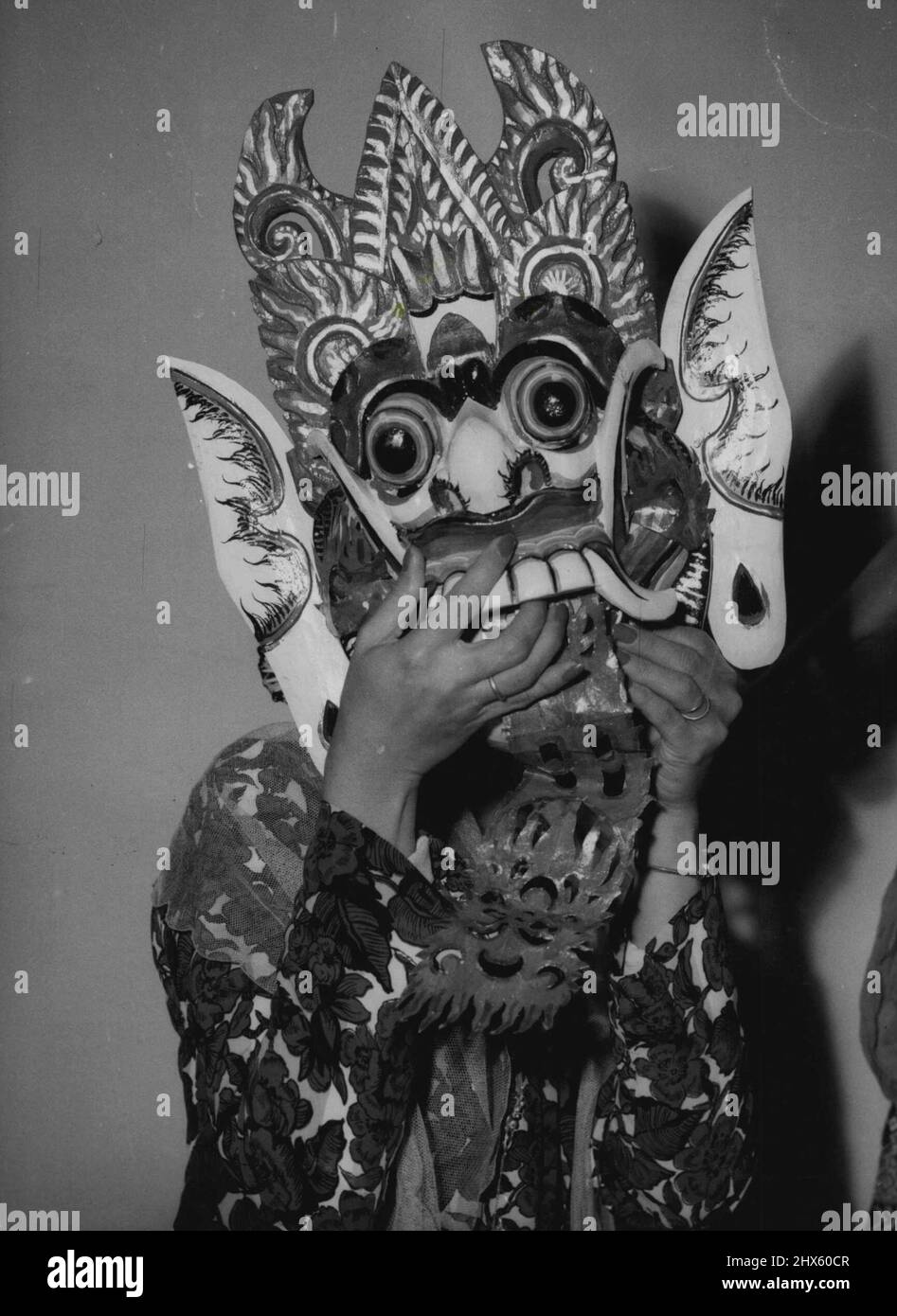 The dancing mask above, worn at the All-Models Exhibition Building today, is intended for a kindly character in a Balinese 'wayang' dance. And here (right) is the face behind the mask Mrs. Salim herself. The masks are one of the many ideas Mrs. Salim is offering in the Indonesian trade display at the exhibition. For example, the glowing purple and pink 'batik' of her costume is a distinctive textile Indonesia wants to market here. The display is to interest Australians in visiting Indonesia, and Stock Photo