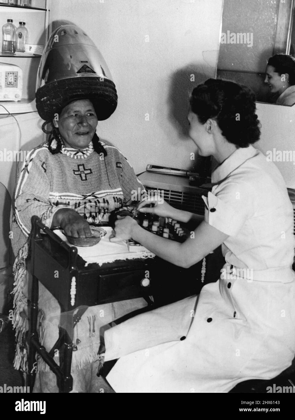 Red Cloud Woman visits Beauty Shop red cloud woman, wife of Chief Spotted Eagle, Headed right for a beauty shop in Banff after driving 42 miles for her tepee at Morley. Here she sits under a hair dryer as Margaret Sadler Manicures her finger nails. January 11, 1941. (Photo by Associated Press Photo).;Red Cloud Woman visits Beauty Shop red cloud woman, wife of Chief Spotted Eagle, Headed right for a beauty shop in Banff after driving 42 miles for her tepee at Morley. Here she sits under a hair dr Stock Photo