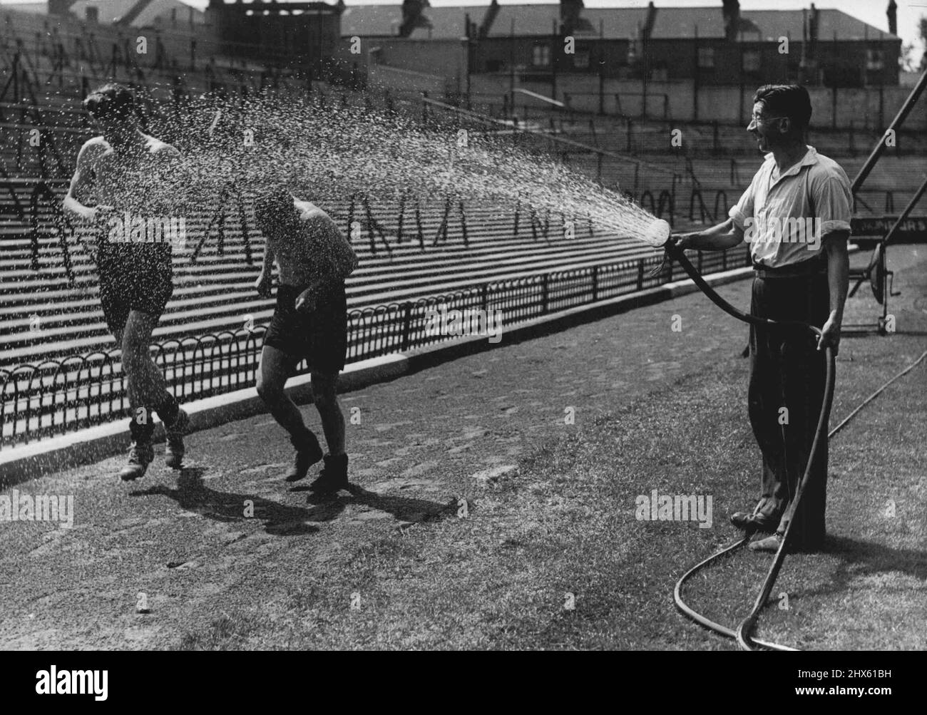 Not On The Training Schedule -- Eryn Jones (left) and goalkeeper latt got an unexpected choler from the groundsman whilst in training at Highbury. The Arsenal F.C. players, in common with most other London footballers, are already hard at work preparing for the coming season their summer recess. August 5, 1947. (Photo by Fox). ;Not On The Training Schedule -- Eryn Jones (left) and goalkeeper latt got an unexpected choler from the groundsman whilst in training at Highbury. The Arsenal F.C. Stock Photo