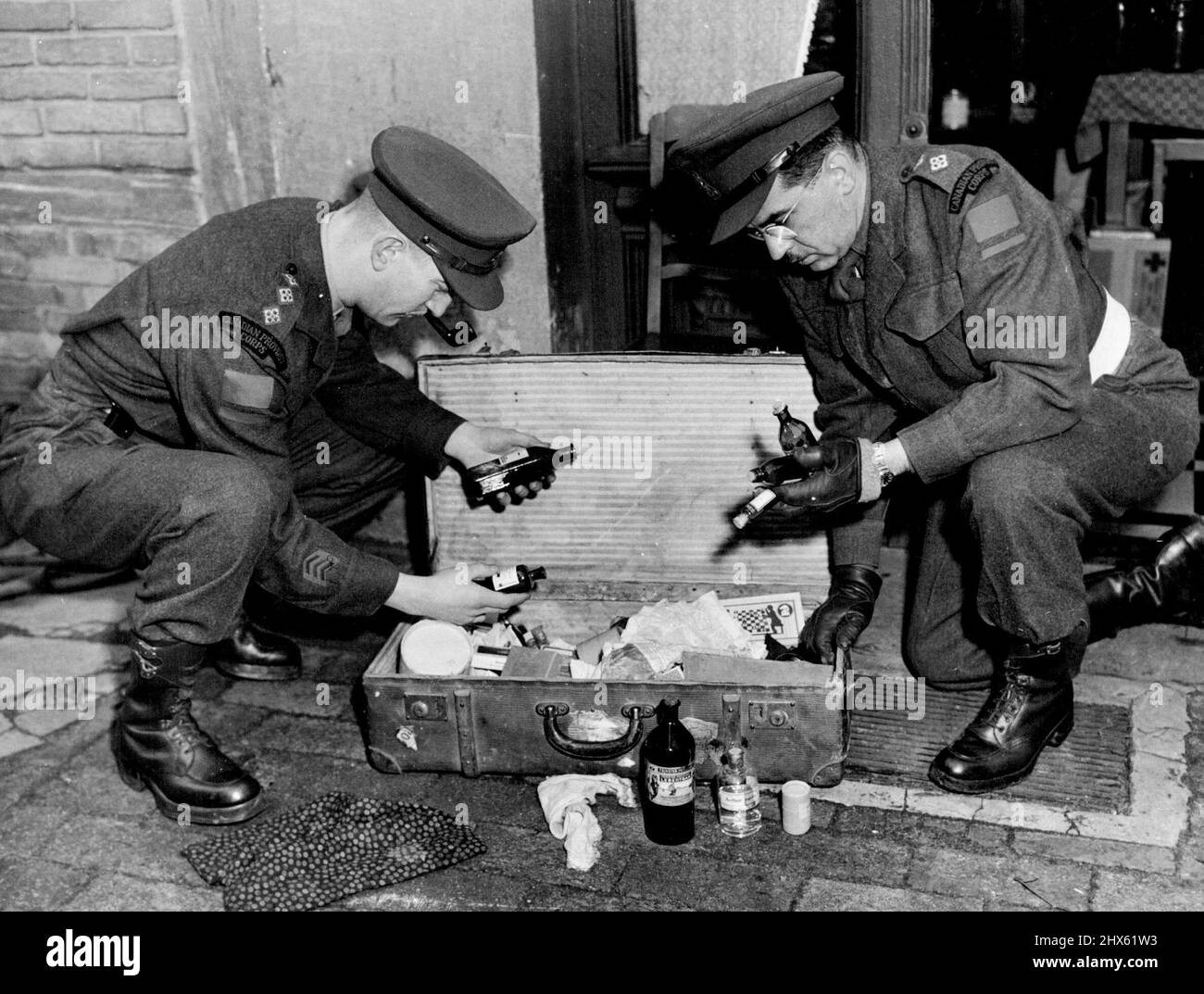 Canadian Provosts said the Canadian Occupation forces in Germany recently arrested a 'black - market' operator who allegedly had been selling poisonous drink. Here is a suitcase full of bottles containing ether, chloroform and other liquids used for distilling poisonous schnapps found during a raid on the home of the accused. The Canadians became ill from drinking the bootleg liquor. March 19, 1948. (Photo by Canadian Information Service).;Canadian Provosts said the Canadian Occupation forces in Stock Photo