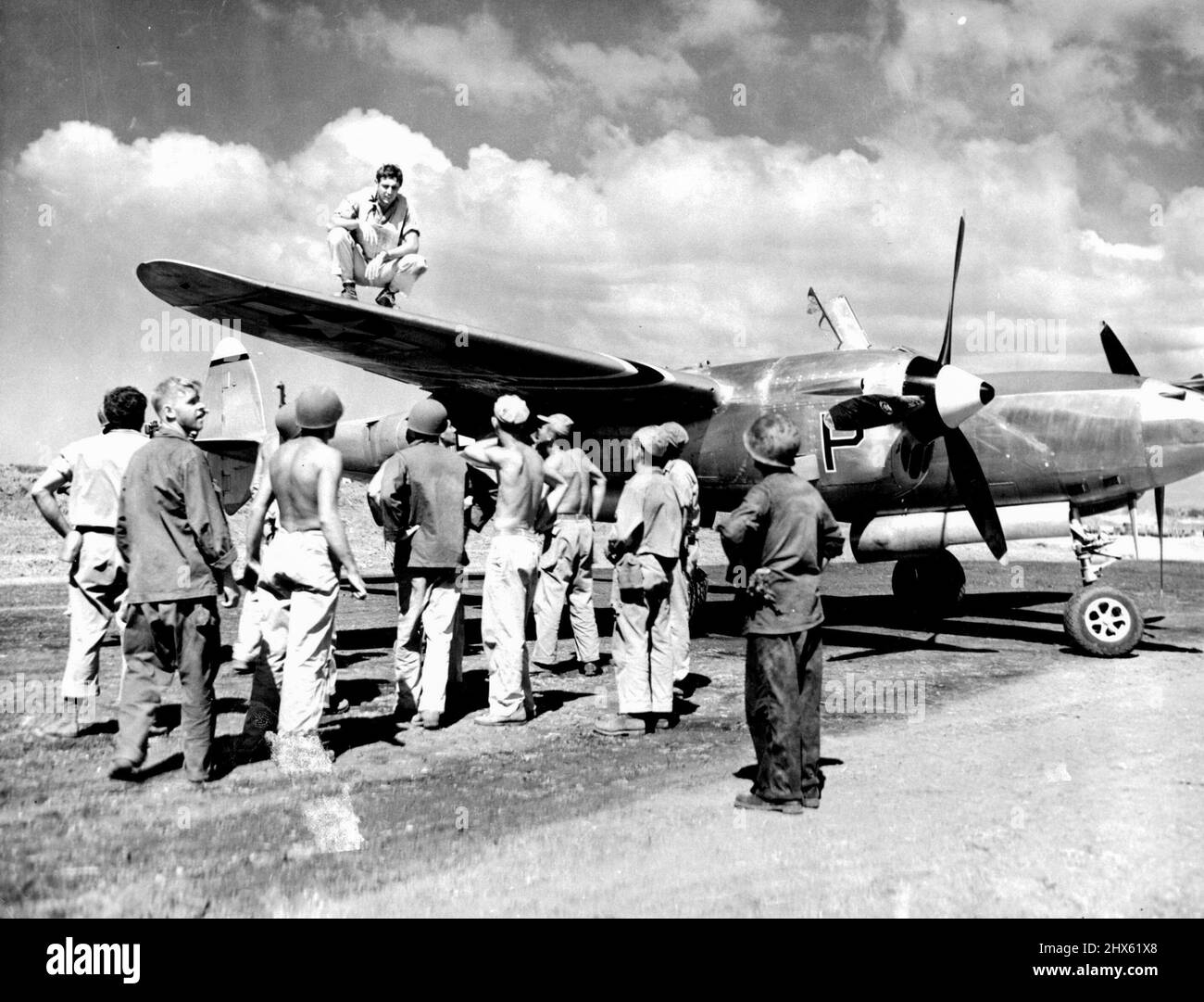 H.B. Graham of Yucaipa, Calif., Squatting on wing of his P-30, and ground crew men look over bullet holes which forced him down after he had knocked one Zero down and damaged another over Mindoro, Philippine Island. January 22, 1945. (Photo by U.S. Army Signal Corps Photo).;H.B. Graham of Yucaipa, Calif., Squatting on wing of his P-30, and ground crew men look over bullet holes which forced him down after he had knocked one Zero down and damaged another over Mindoro, Philippine Island. Stock Photo