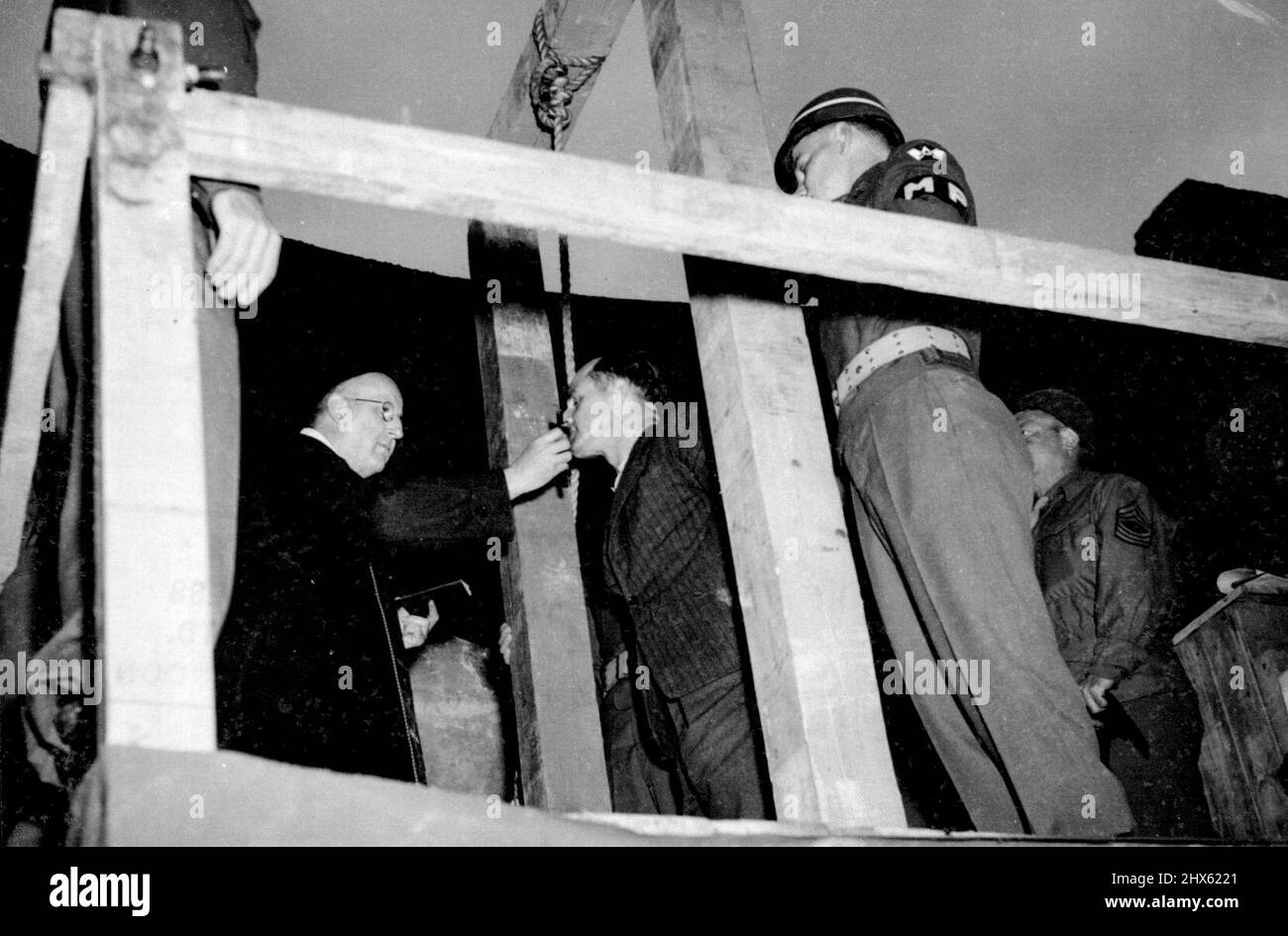 Three German Civilians Execited-First Picture -- Peter back kisses the crucifix held by a Catholic priest before the noose is placed around his neck. Three German civilians, the first was criminals to be tried in Germany, were hanged at dawn on June 29, at the Military. Prison at Rhinebach. All three were found guilty of the murder of an American airman who parachuted to earth from his blazing bomber last August 15. The three men, Peter back, a cripple and rural leader of the Nazi Party; Peter Stock Photo
